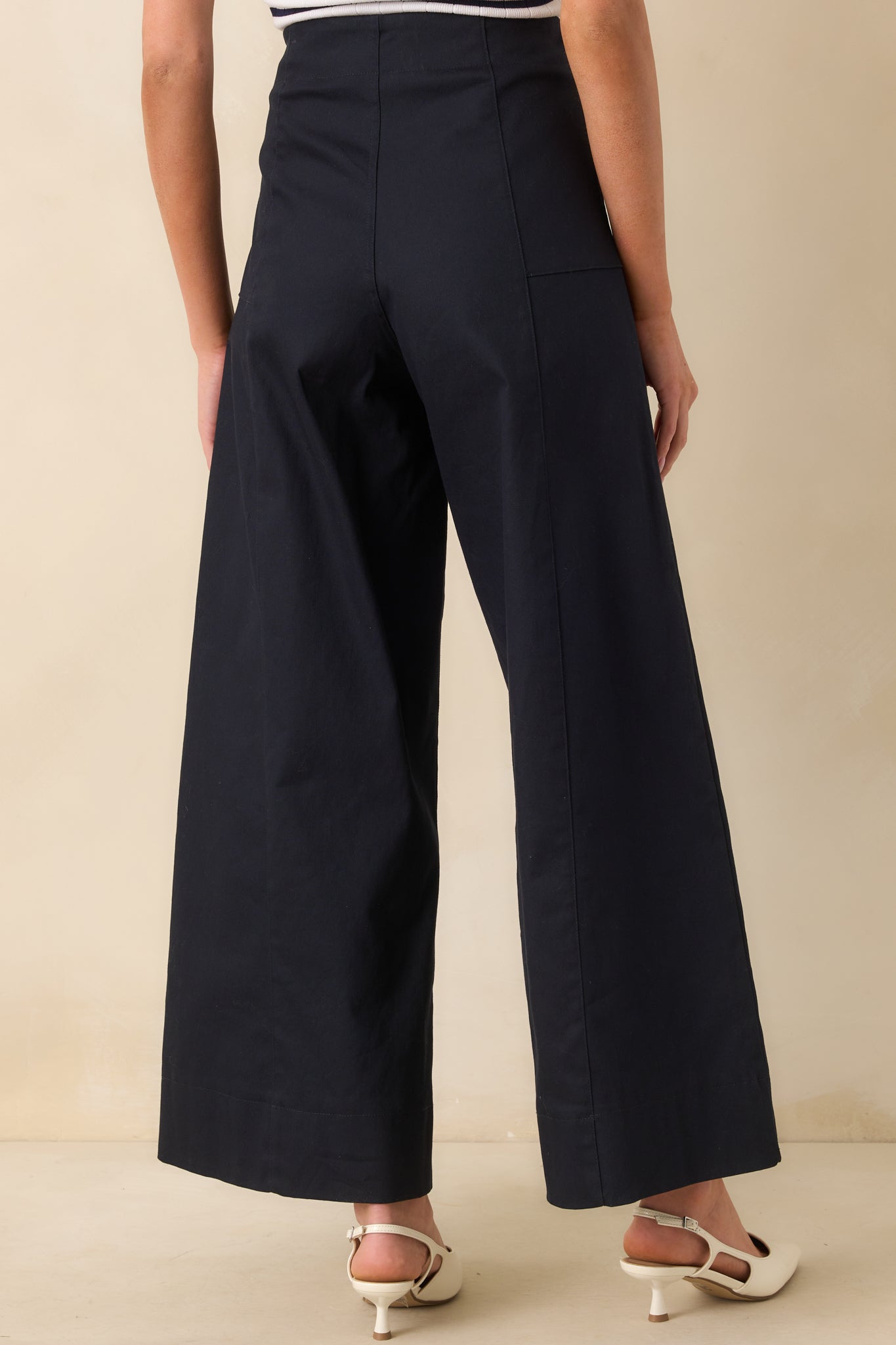 A view from behind showing the wide leg cut and smooth high waist of the navy pants.
