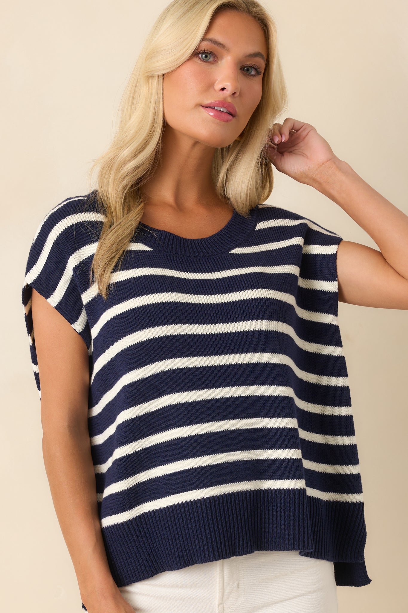 Front-facing view of the navy sweater vest showing the ribbed crew neckline, white horizontal stripes, and short cap sleeves.