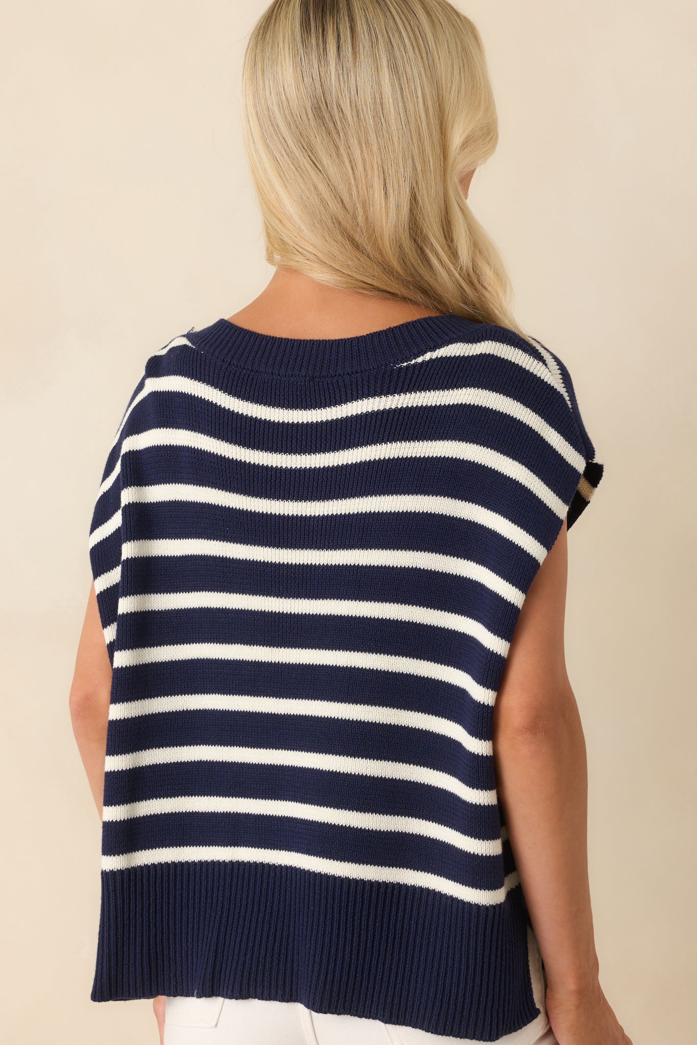 A view from behind showing the solid navy knit, ribbed hemline, and shape of the cap sleeves without the stripe pattern.