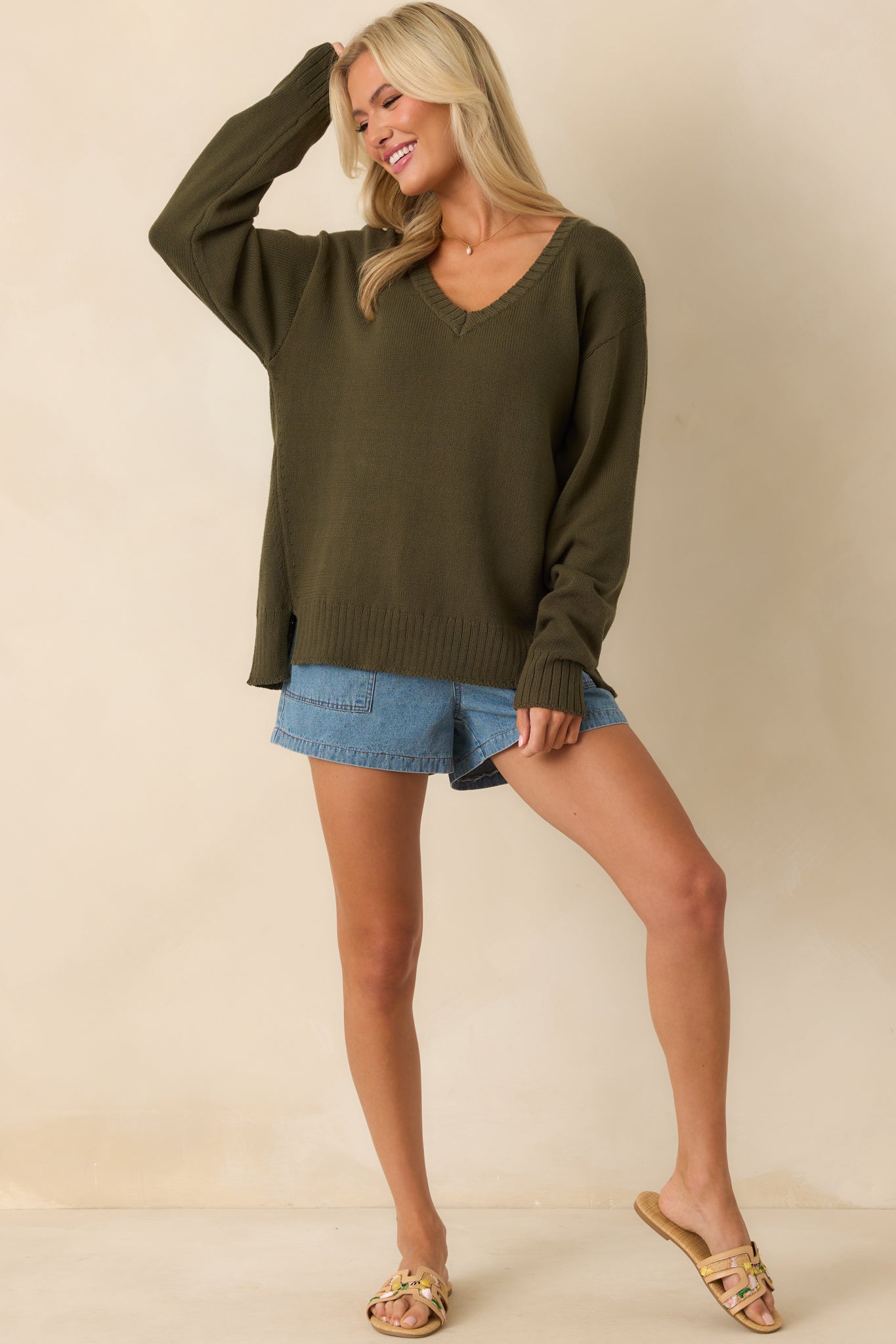 A full body front view of the olive green sweater showcasing its V-neckline and relaxed fit.