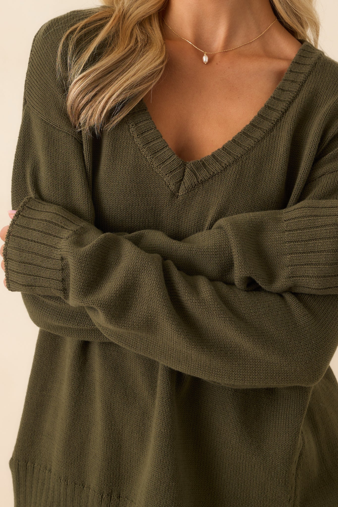 A close-up detail of the olive green cotton knit fabric showing fine ribbed trim and stitching