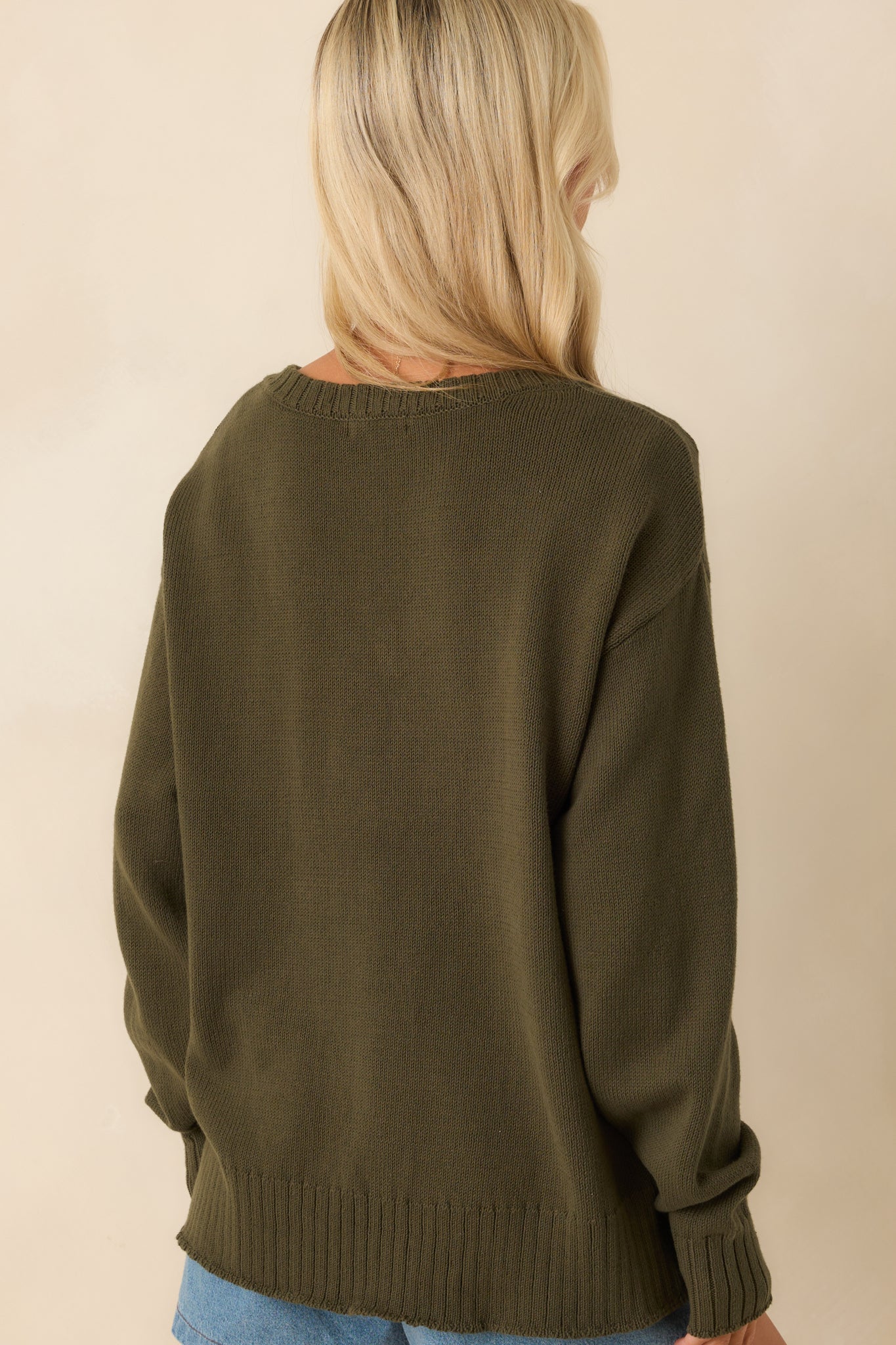 A back view of the sweater displaying the extended drop shoulders, relaxed shape, and ribbed back hem.
