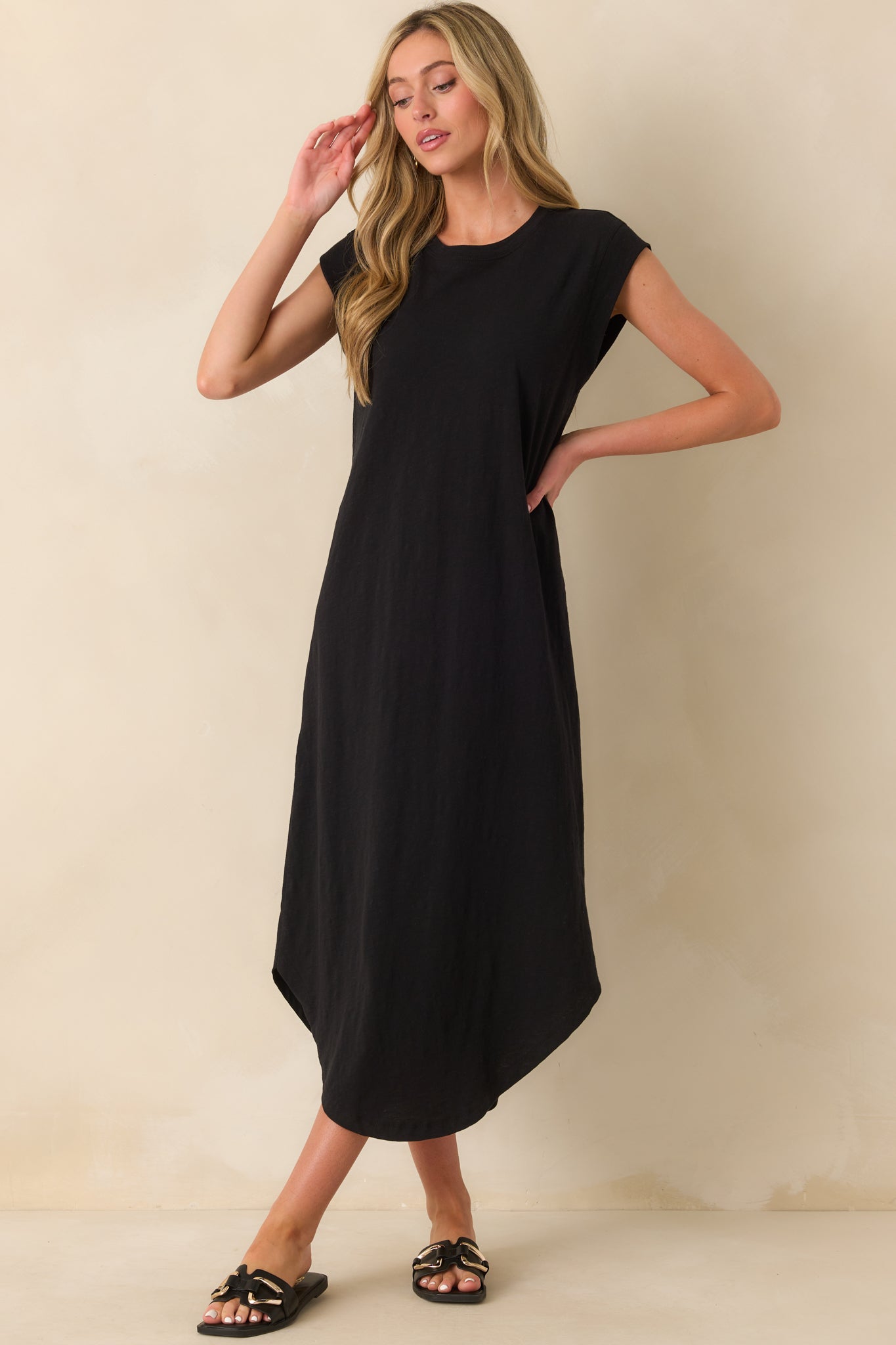 A black midi dress with short cap sleeves and scoop hem flowing naturally for a relaxed look.