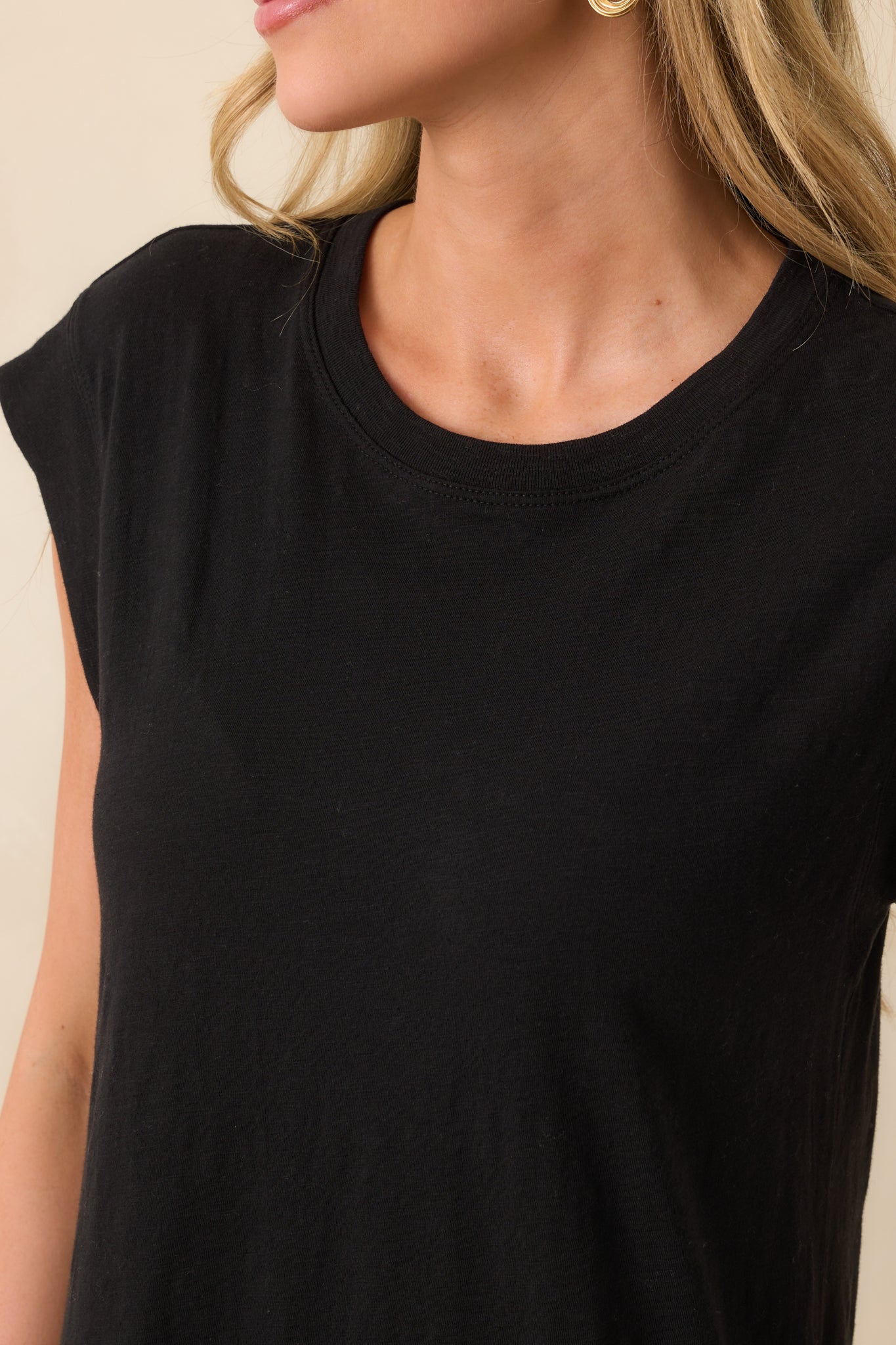 Detailed look at black midi dress fabric, crew neckline, and cap sleeve construction.