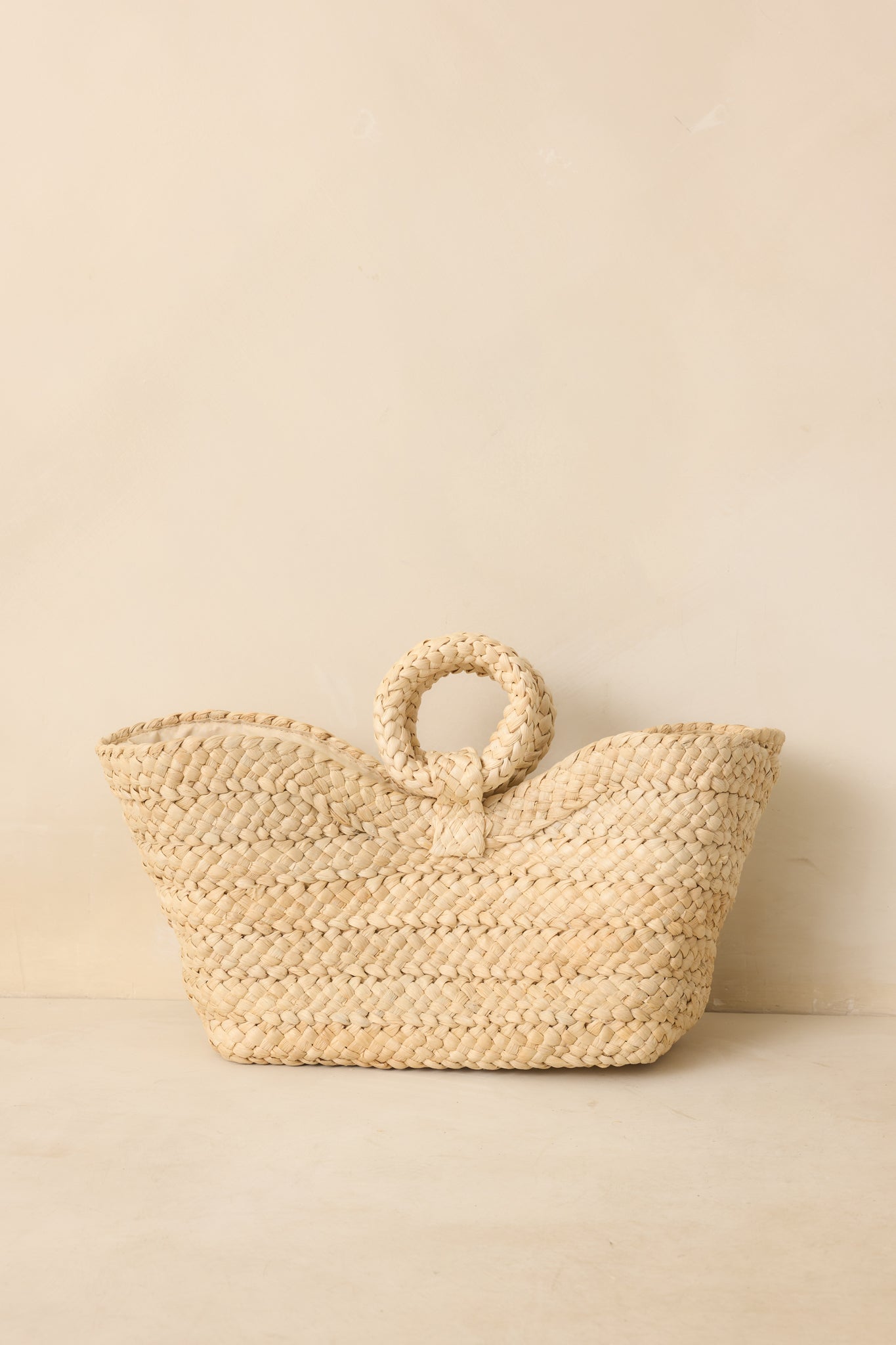 Full body front view showing the ivory raffia handbag with an open tote design and circular woven handles.