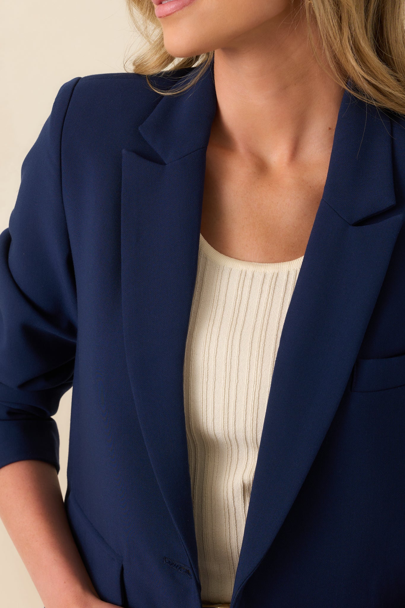 Close-up view of the navy blazer showing the button-front closure, lapel detail, and pocket stitching.