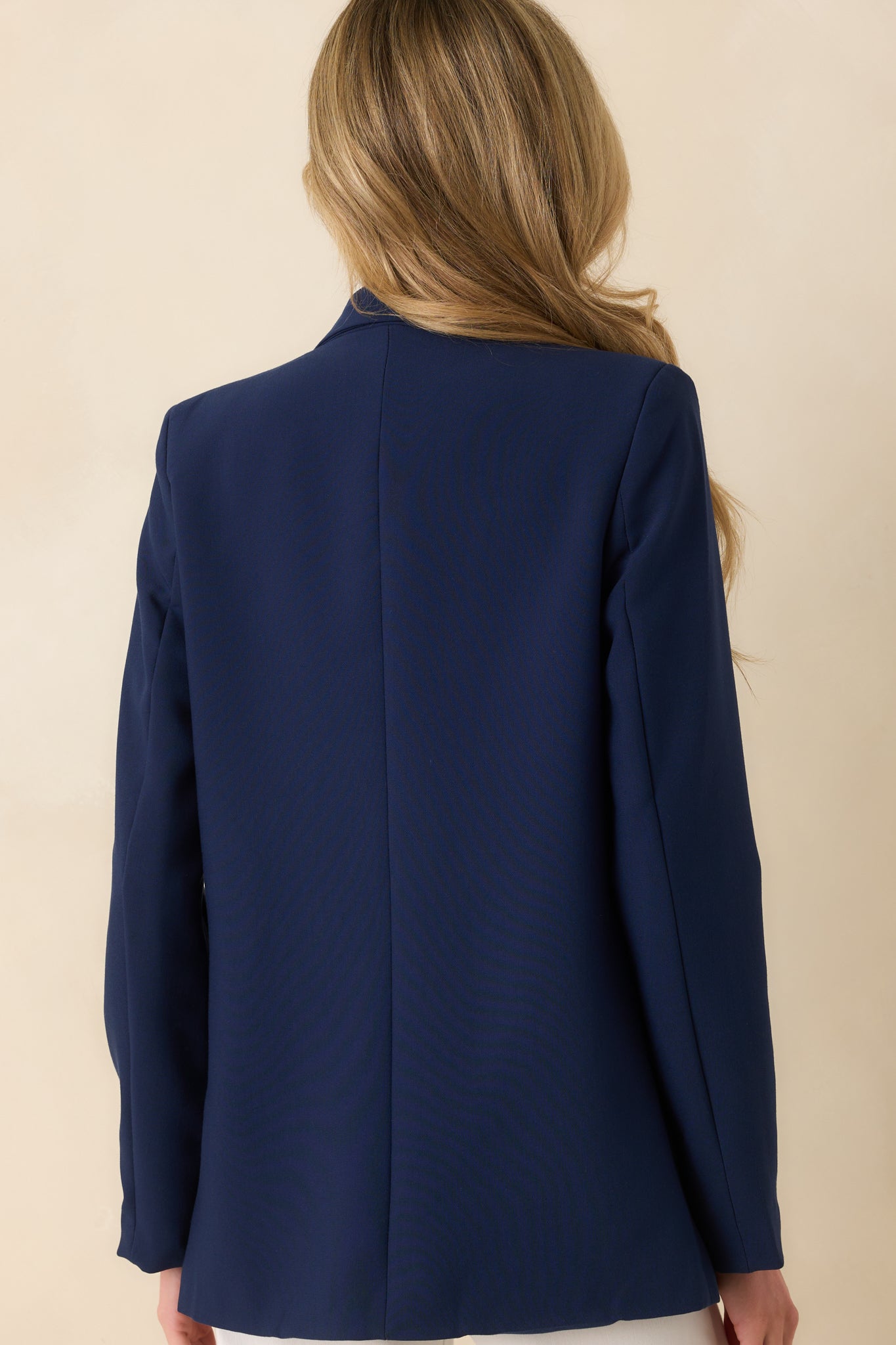 Back view of the navy blazer highlighting the tailored back and long sleeve construction.