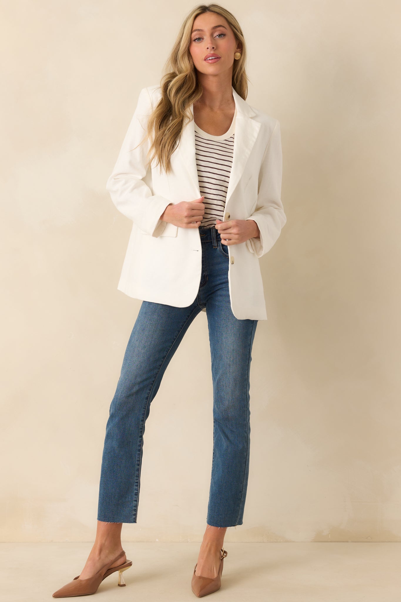 A full view of the white blazer with a collared neckline, half button front, and long sleeves.