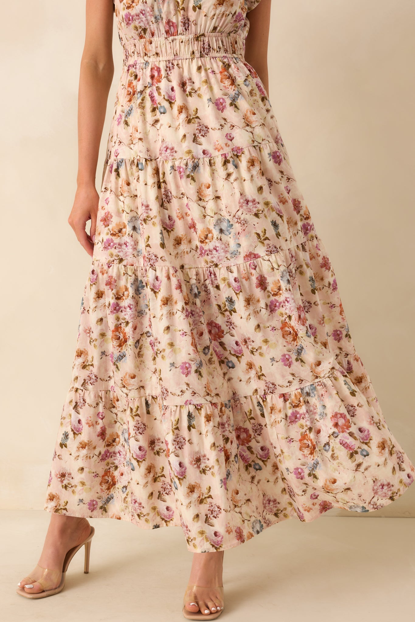 A close cropped view focusing on the skirt of the dress, capturing its floral print pattern, tiered design, and overall flow.