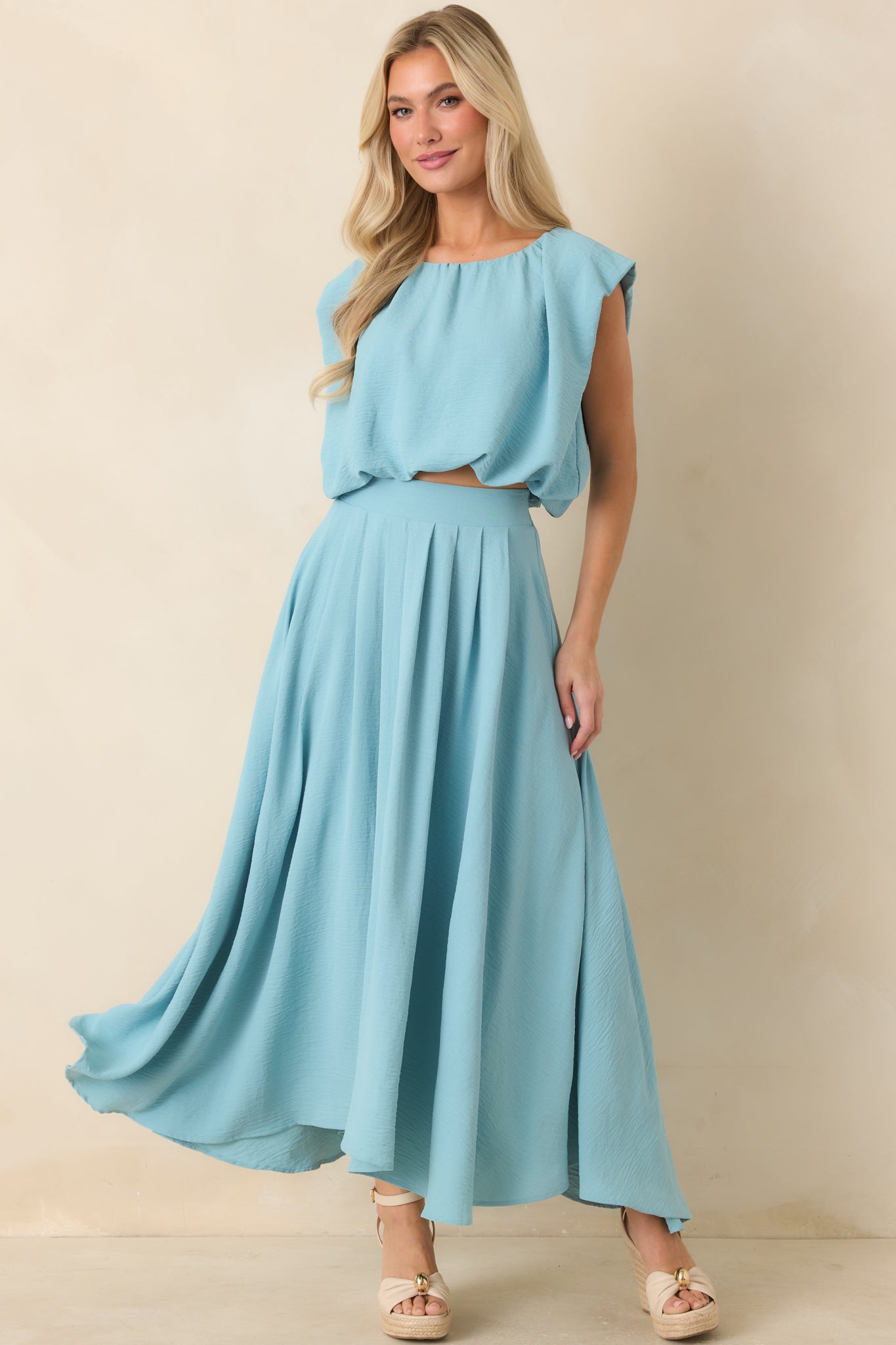 Bright turquoise top with a relaxed draped shape, elasticized hem, and softly gathered neckline detail.