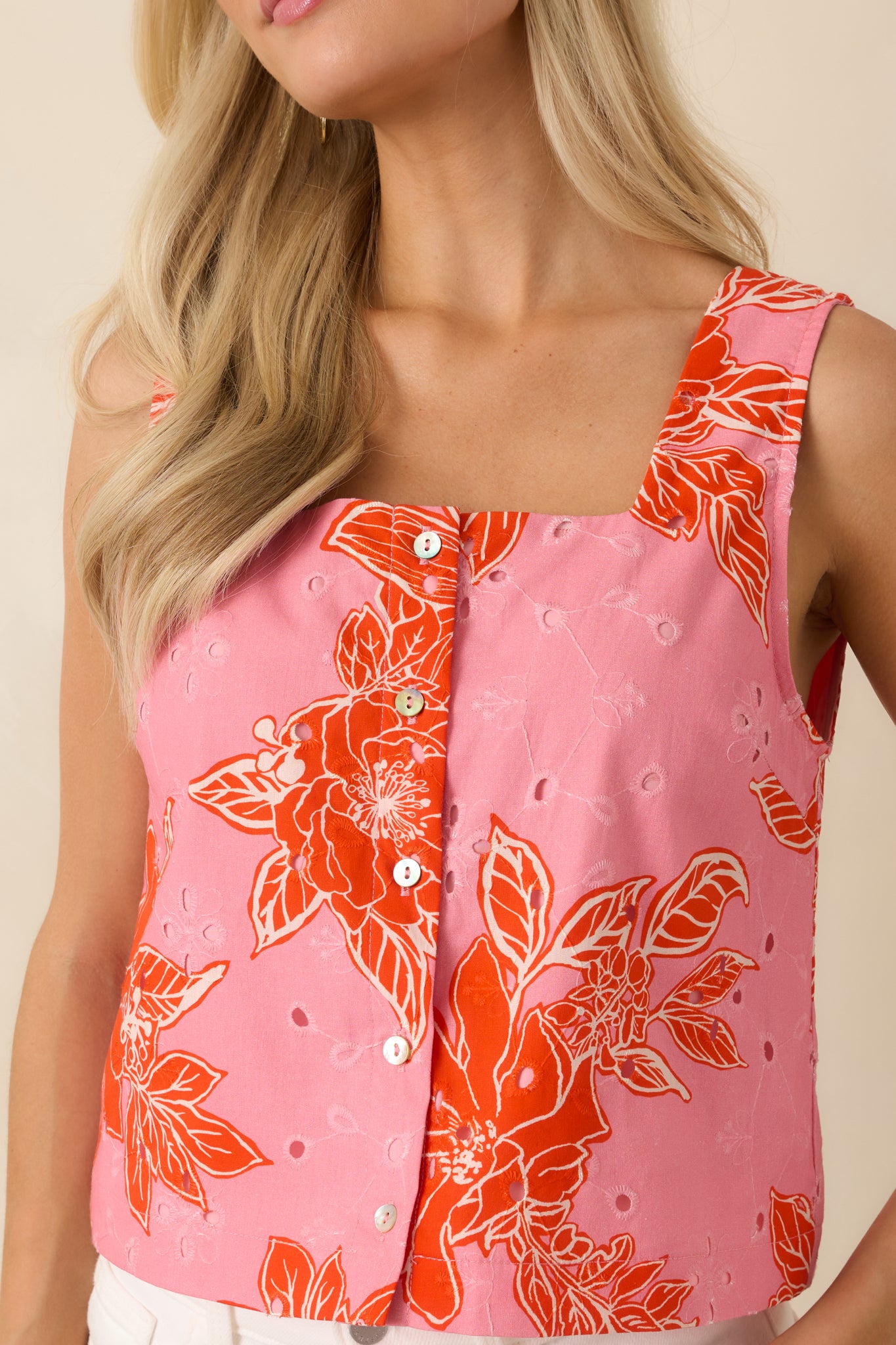 Detailed look at cotton eyelet fabric with pink and red floral print and button front stitching.
