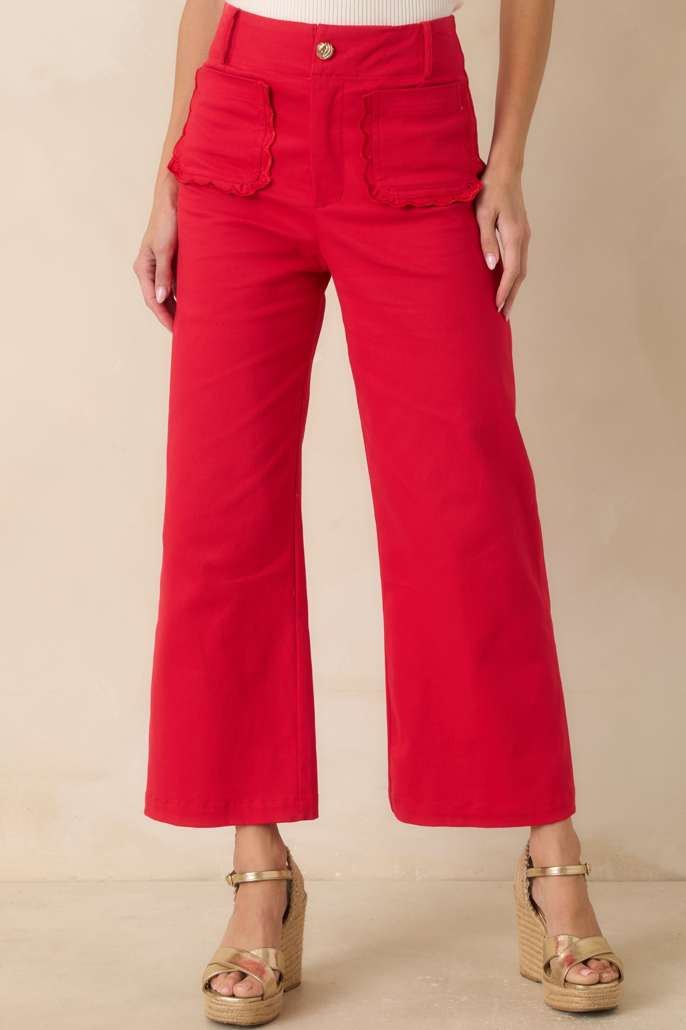 Close view of the high-rise waistband with belt loops and zip fly with button closure on the cherry red pants.