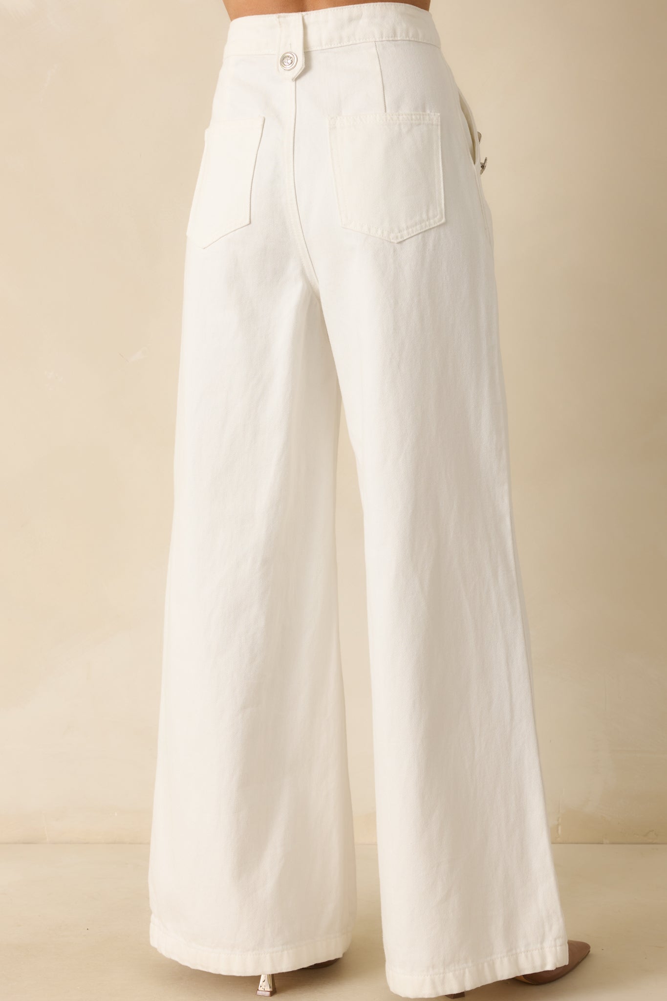 Rear view of the white jeans showing wide legs and back pocket detailing.