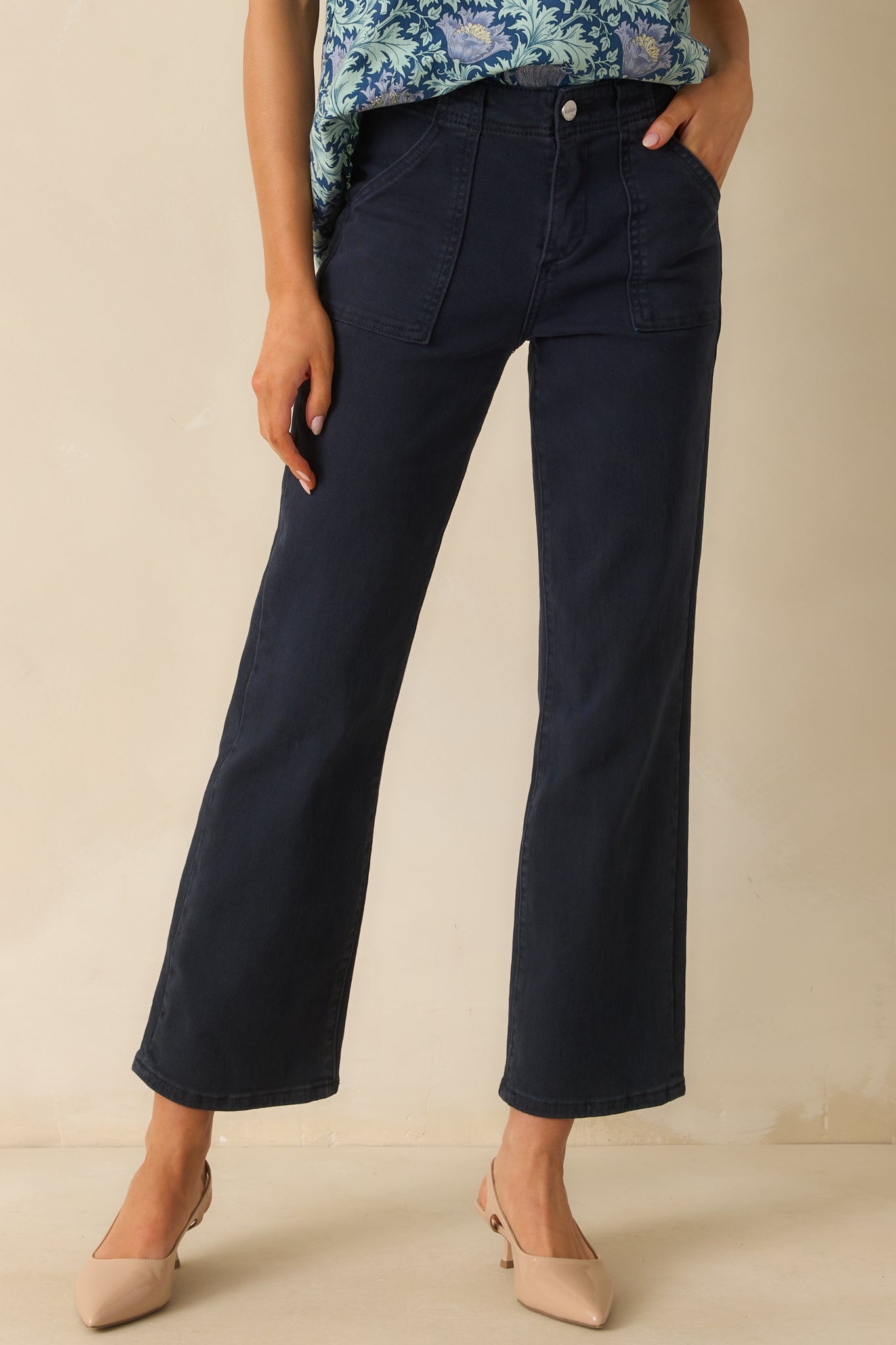 A cropped front view focusing on the waistband, button, and zipper closure.