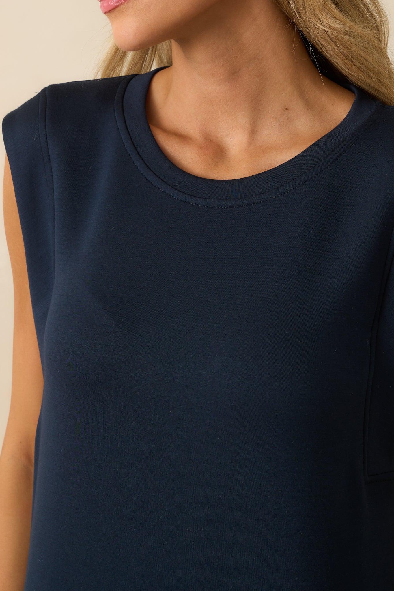 Detailed view of the crew neckline and cap sleeve stitching on the navy fabric.