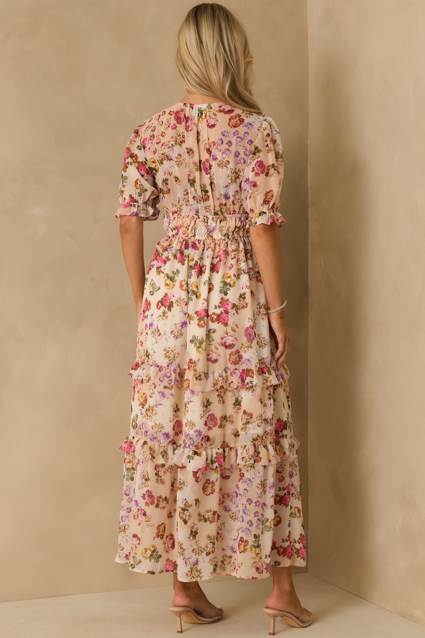 Rear view of beige midi dress with pink florals, elastic waistbands, and ruffled tiered skirt.