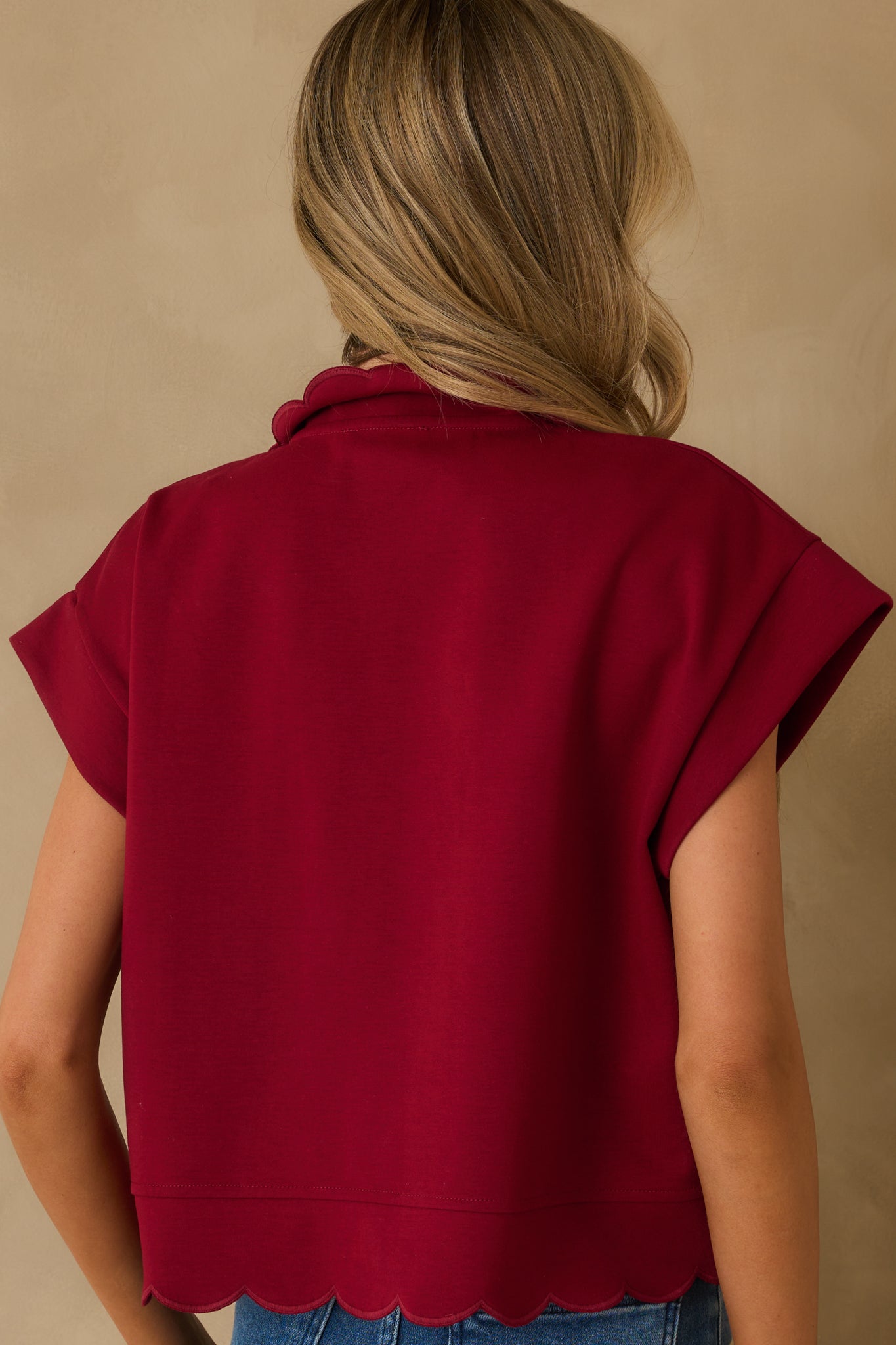 Rear view of the burgundy pullover showing relaxed fit and embroidered scallop hem along the back.