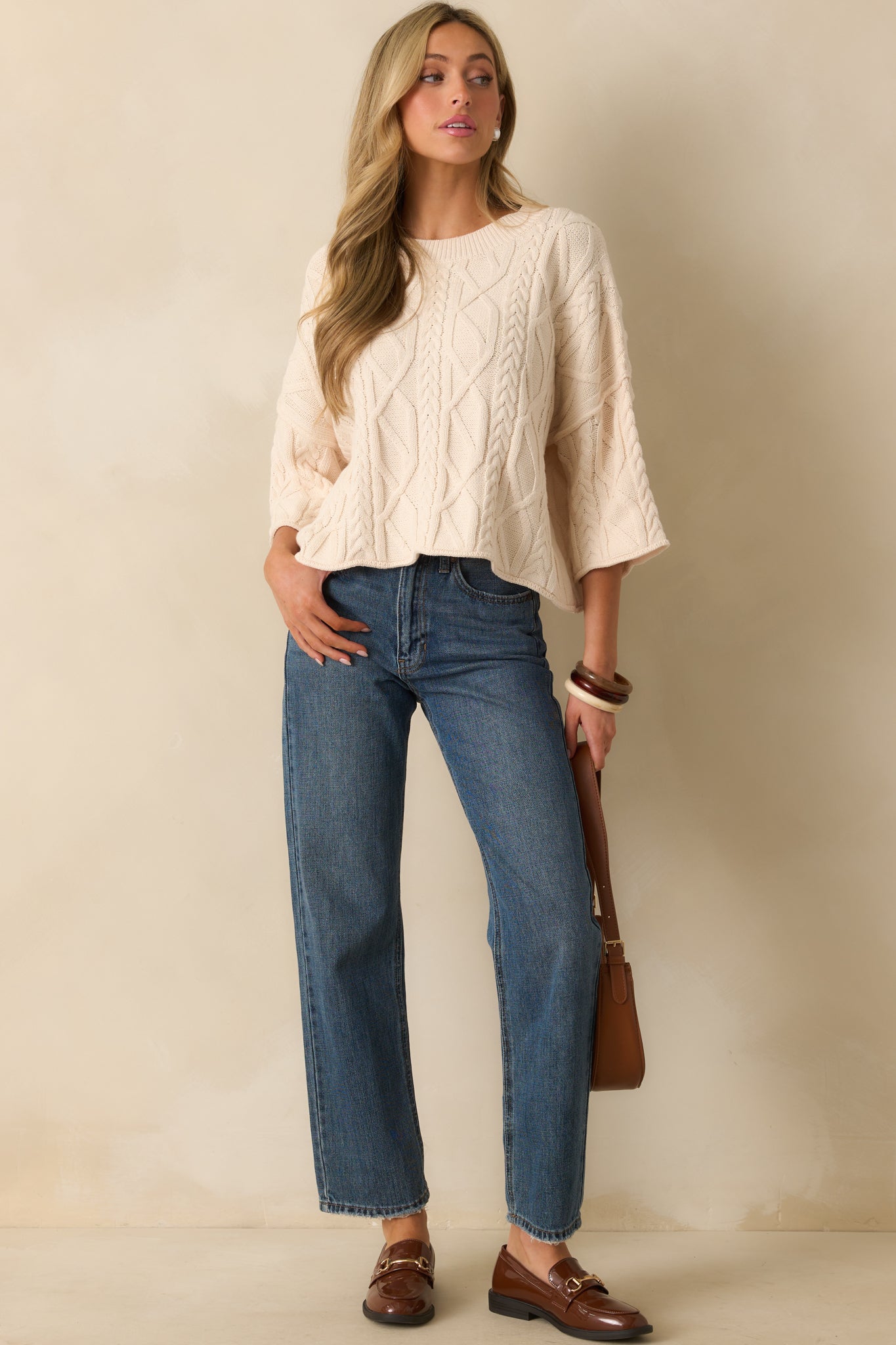 A full front view of the ivory sweater featuring a ribbed crew neckline and 3/4 length sleeves.
