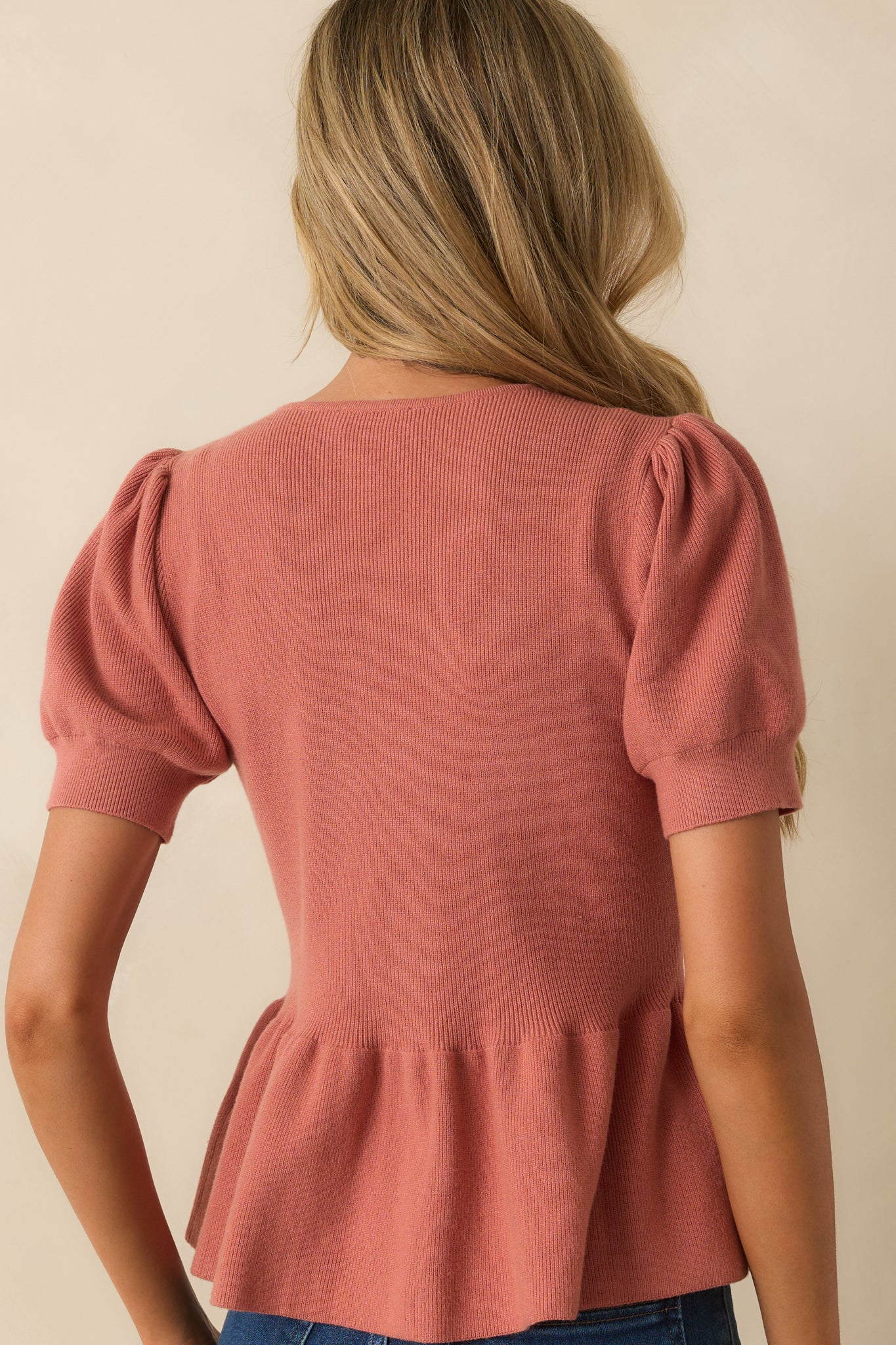 Rear view of the rose pink top showing the peplum silhouette and short sleeves.