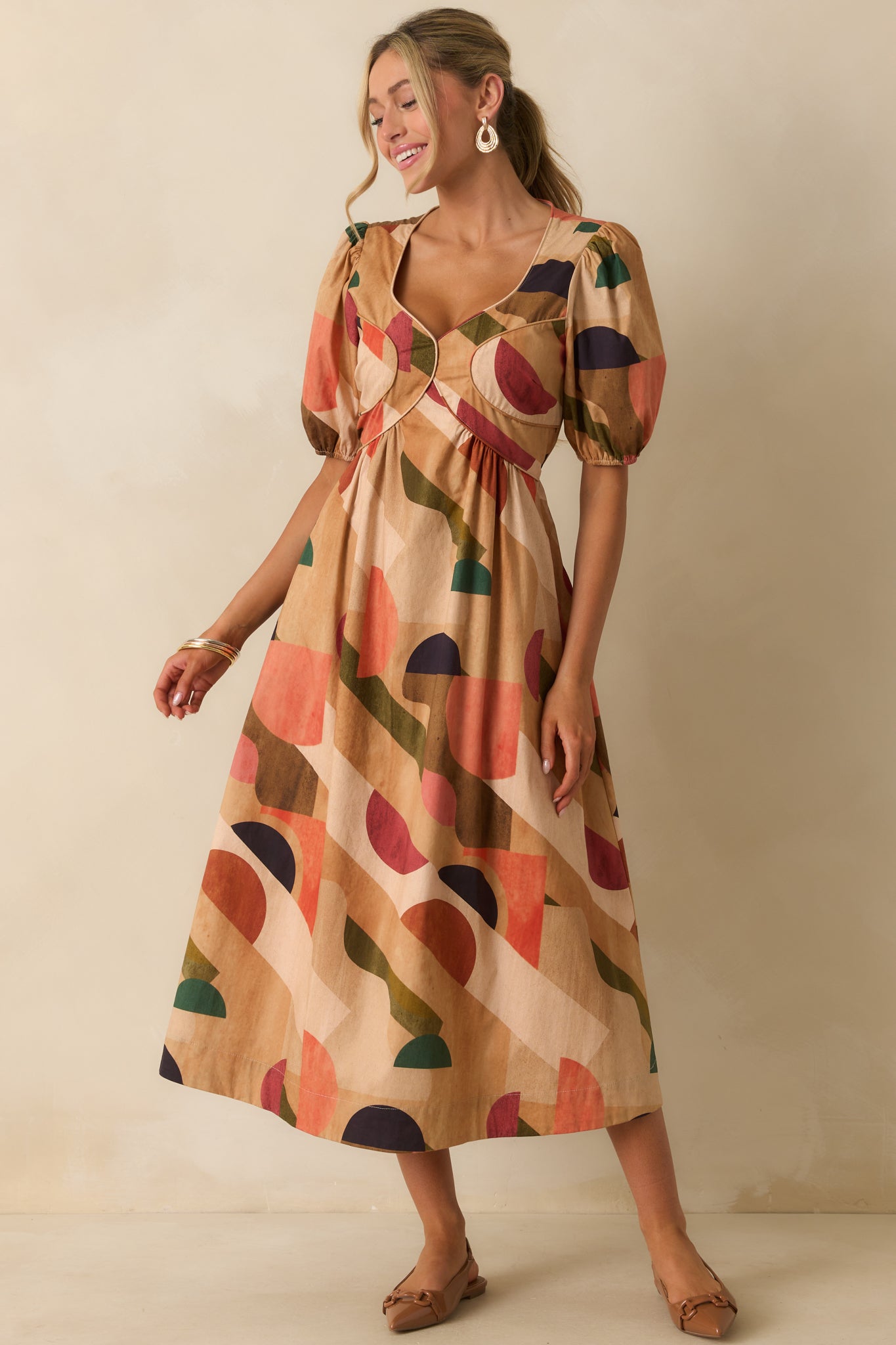 Front view of tan dress highlighting functional pockets and midi length skirt.
