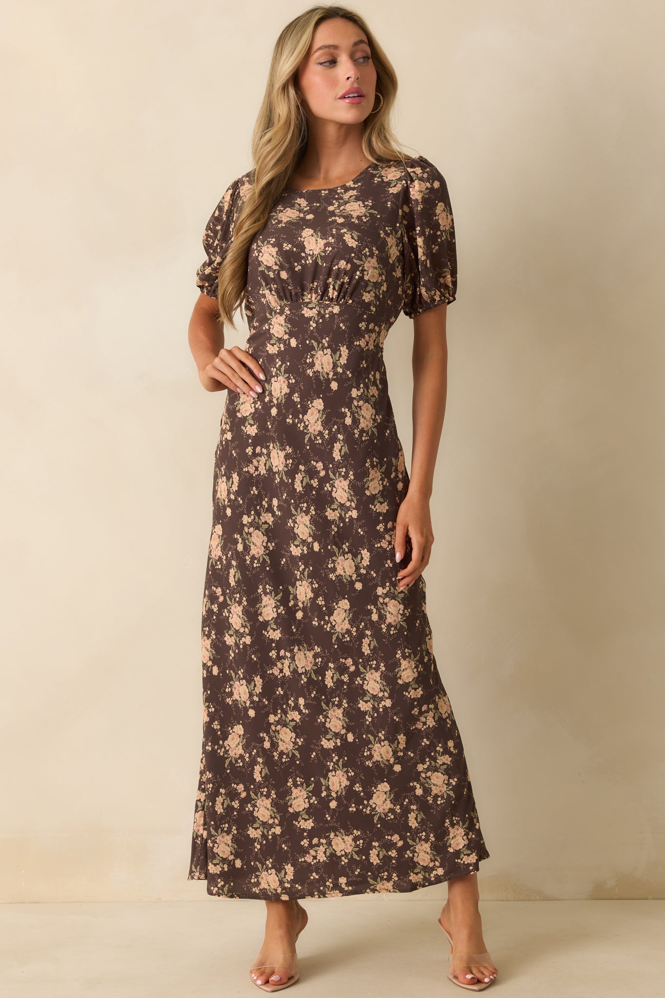 Chocolate brown dress with pink and green floral print and a round neckline.