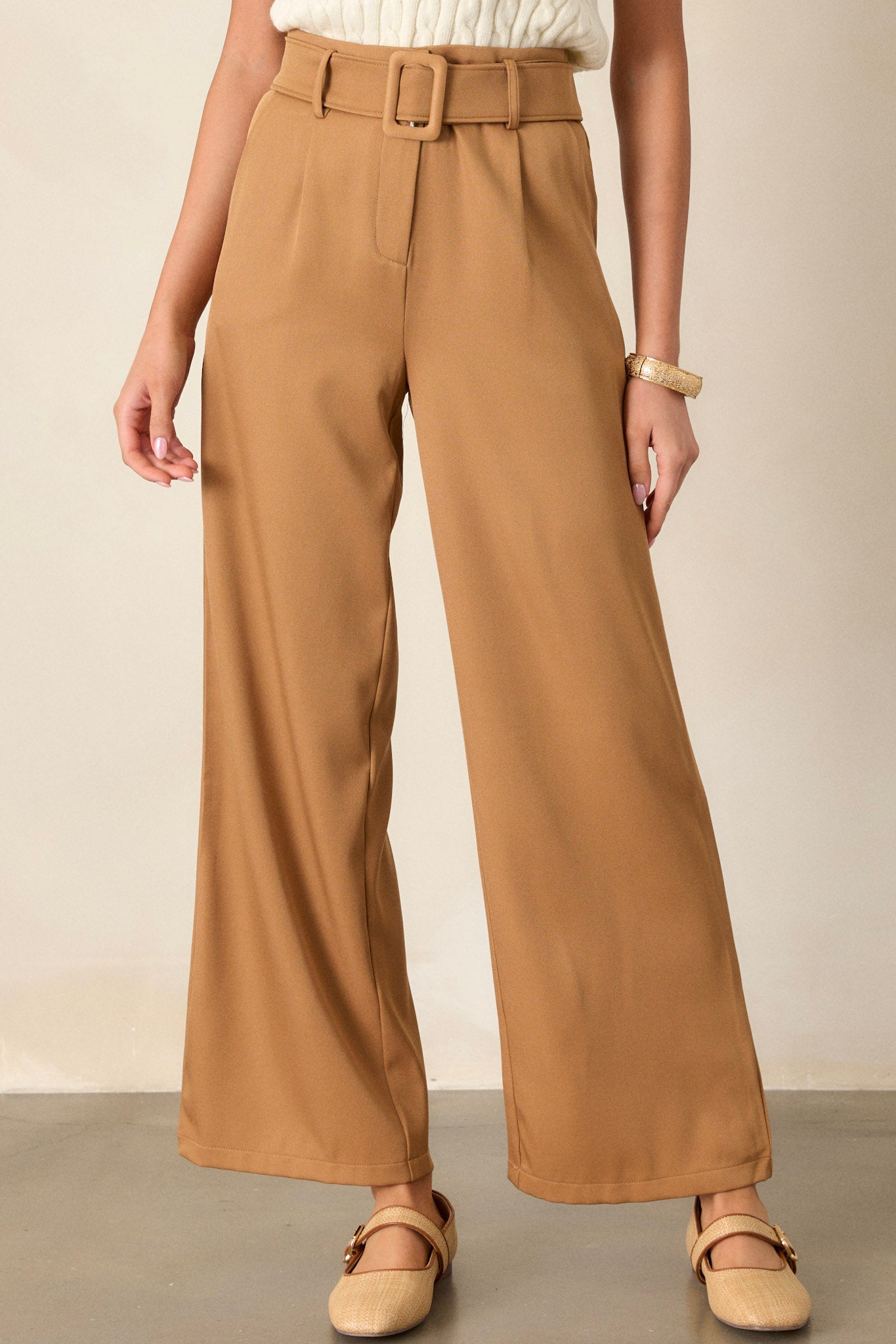 These brown belted pants feature a high waisted design, a hook and bar closure, a built in adjustable cloth belt, functional pockets and a wide leg.