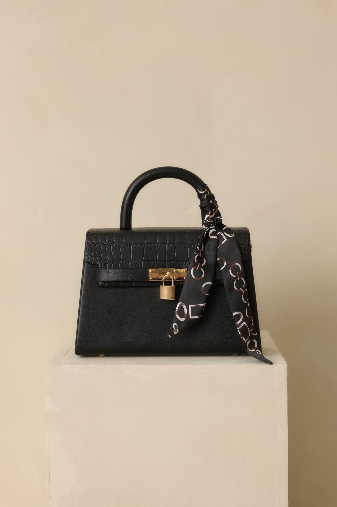 Cropped angled photo focusing on the structured shape and croc-embossed flap of the black handbag.
