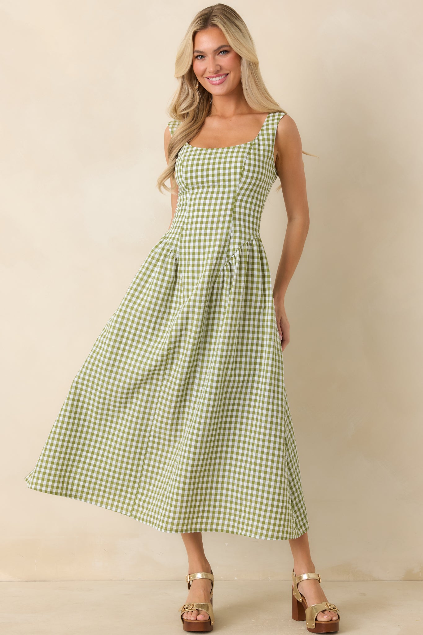Green gingham midi dress with square neckline, wide straps, and a fitted bodice flowing into a full skirt.