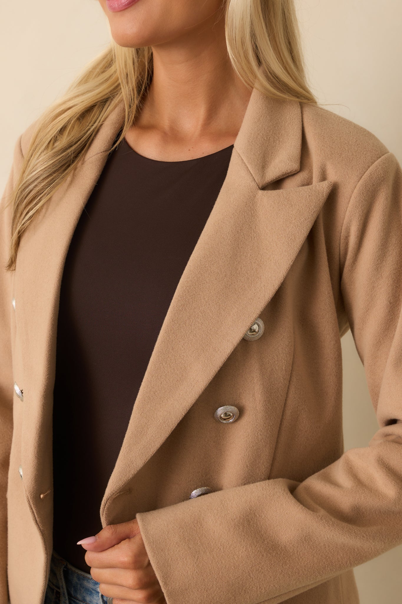 A close-up of the blazer showing silver embellished buttons, lapel collar, and pocket stitching details.