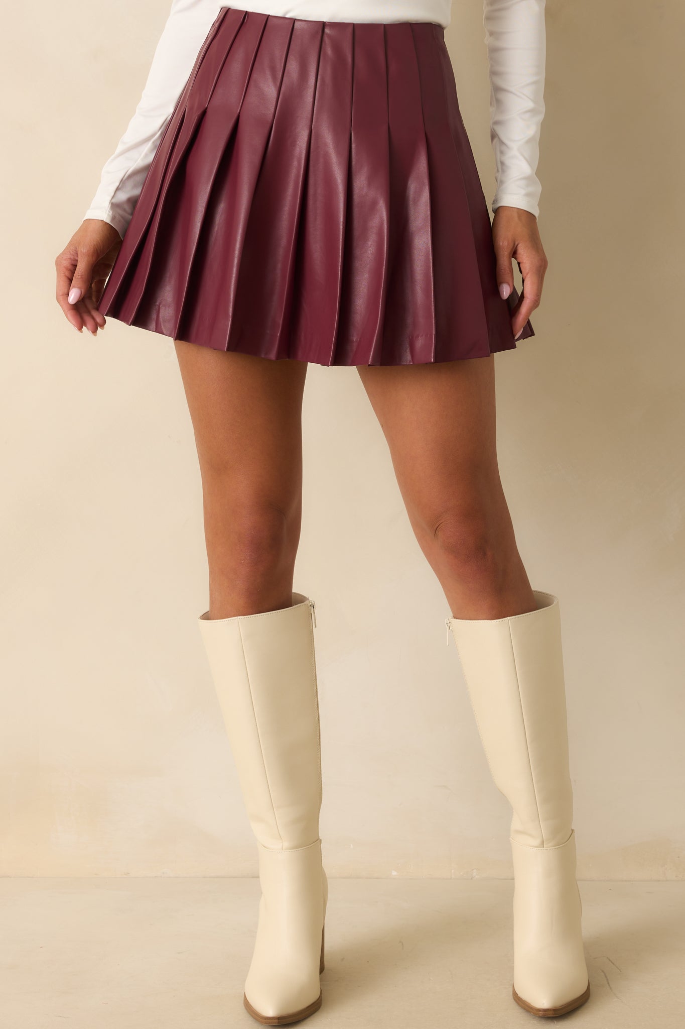 Close view of the high-rise waist and box-pleated details on the wine red faux leather skirt.