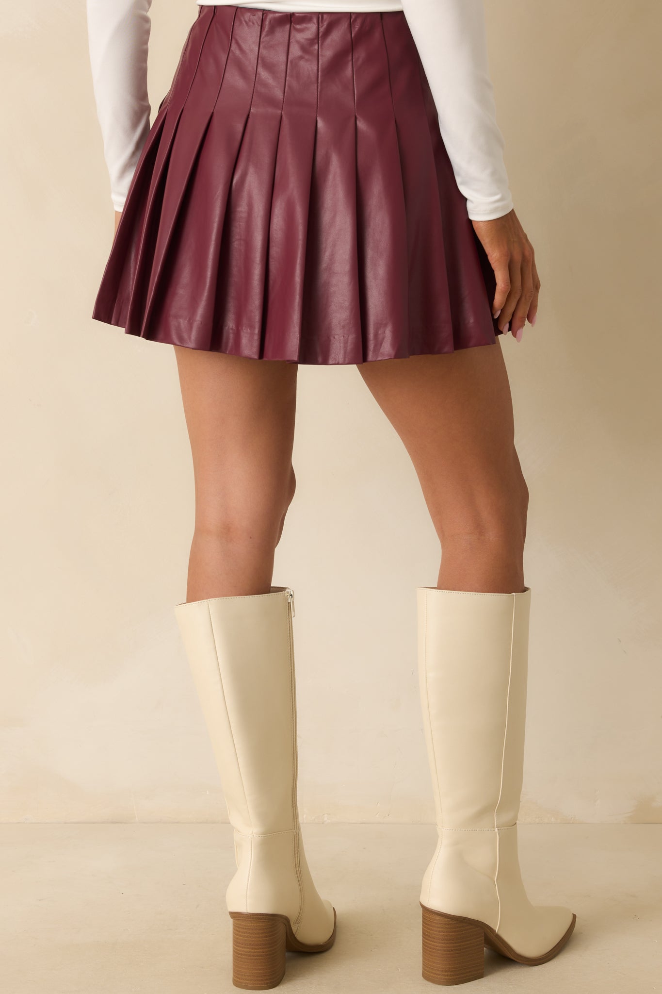 Rear view of the wine red mini skirt showing box-pleated design and high-rise waist.
