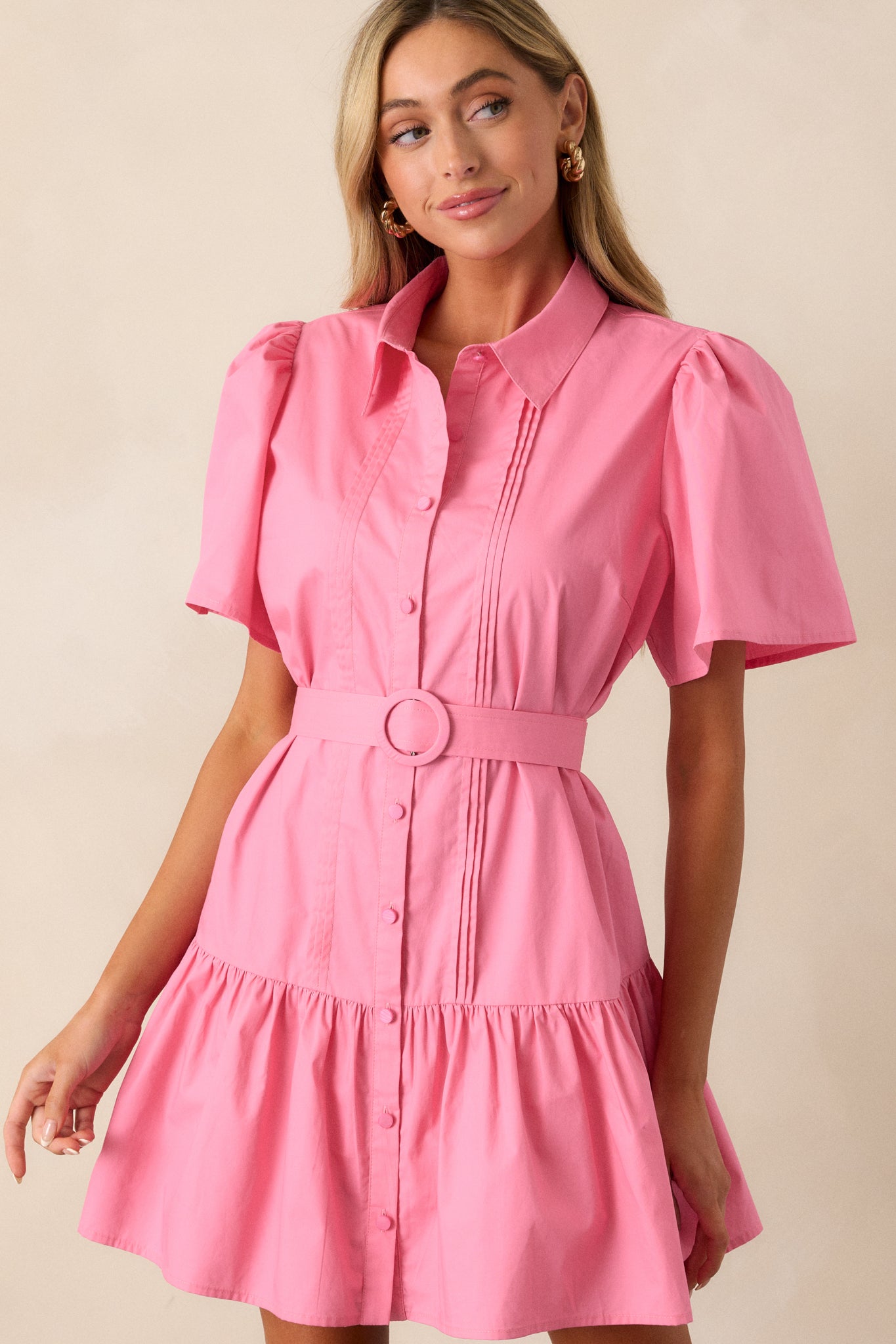 A detailed view of the short sleeves and pin tuck accents of the pink mini dress, showcasing its tailored elements.
