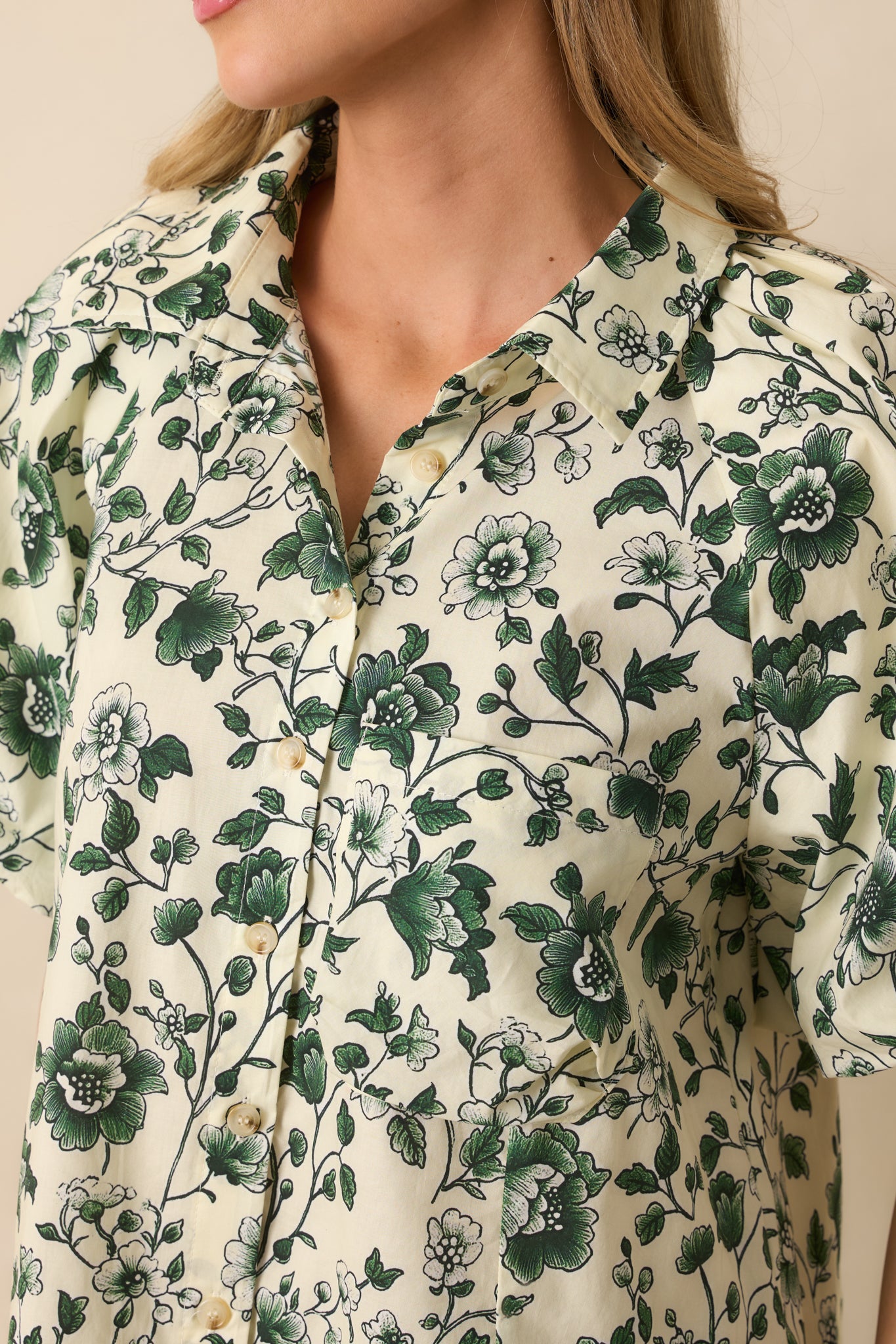 Detailed look at the floral print, button closure, and elastic cuff texture.