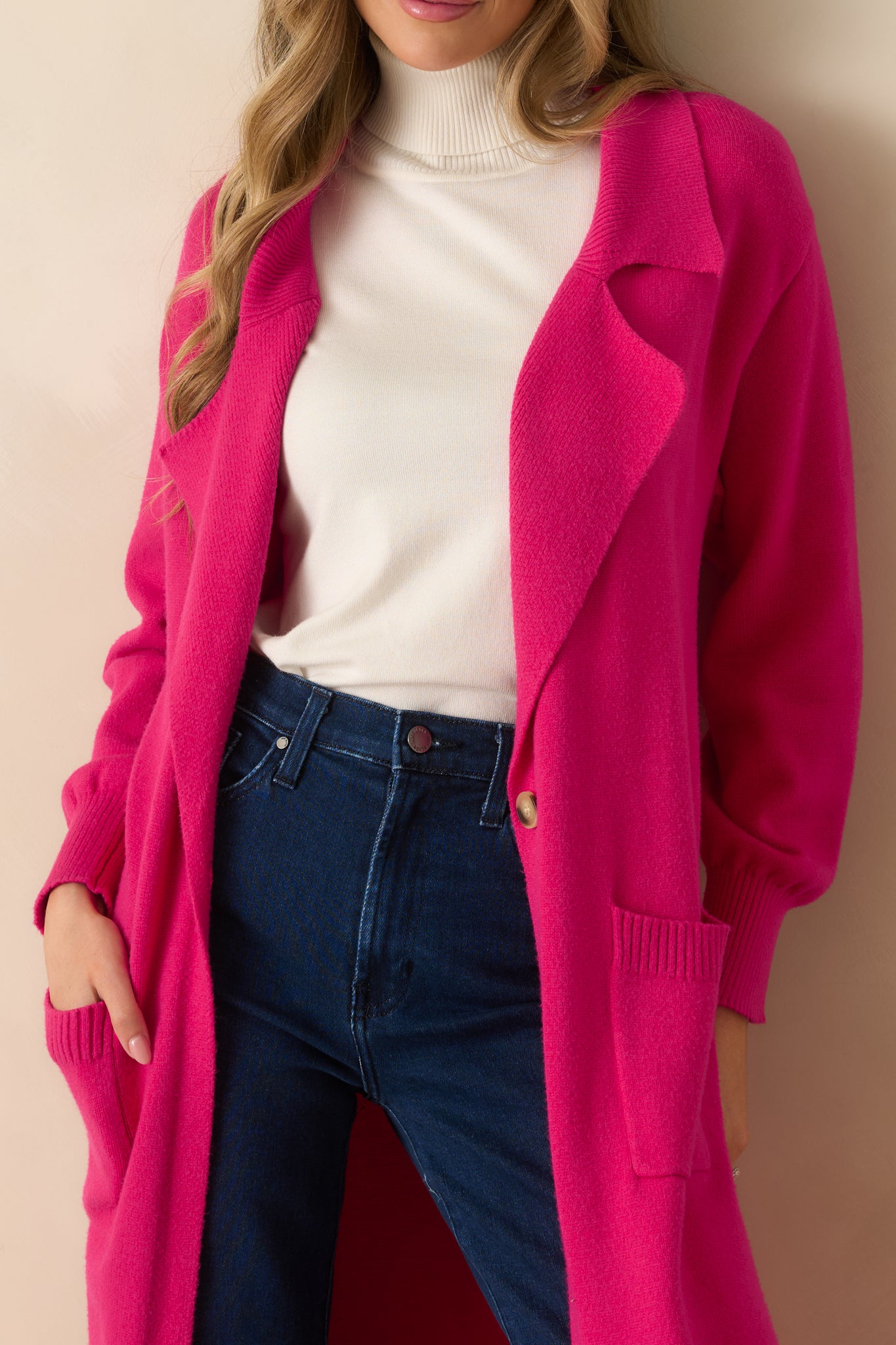 Close-up of the hot pink cardigan showing the lapel collar, button closure, and knit texture.