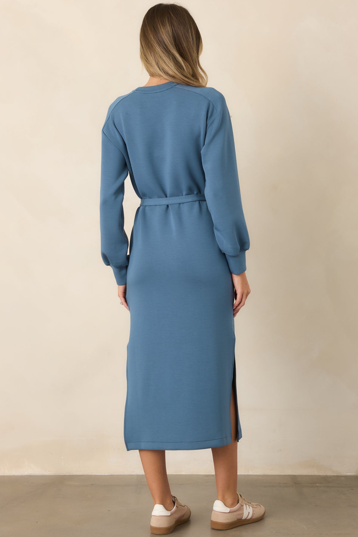 Back view of blue midi dress with long sleeves, self-tie waist, and side hem slit