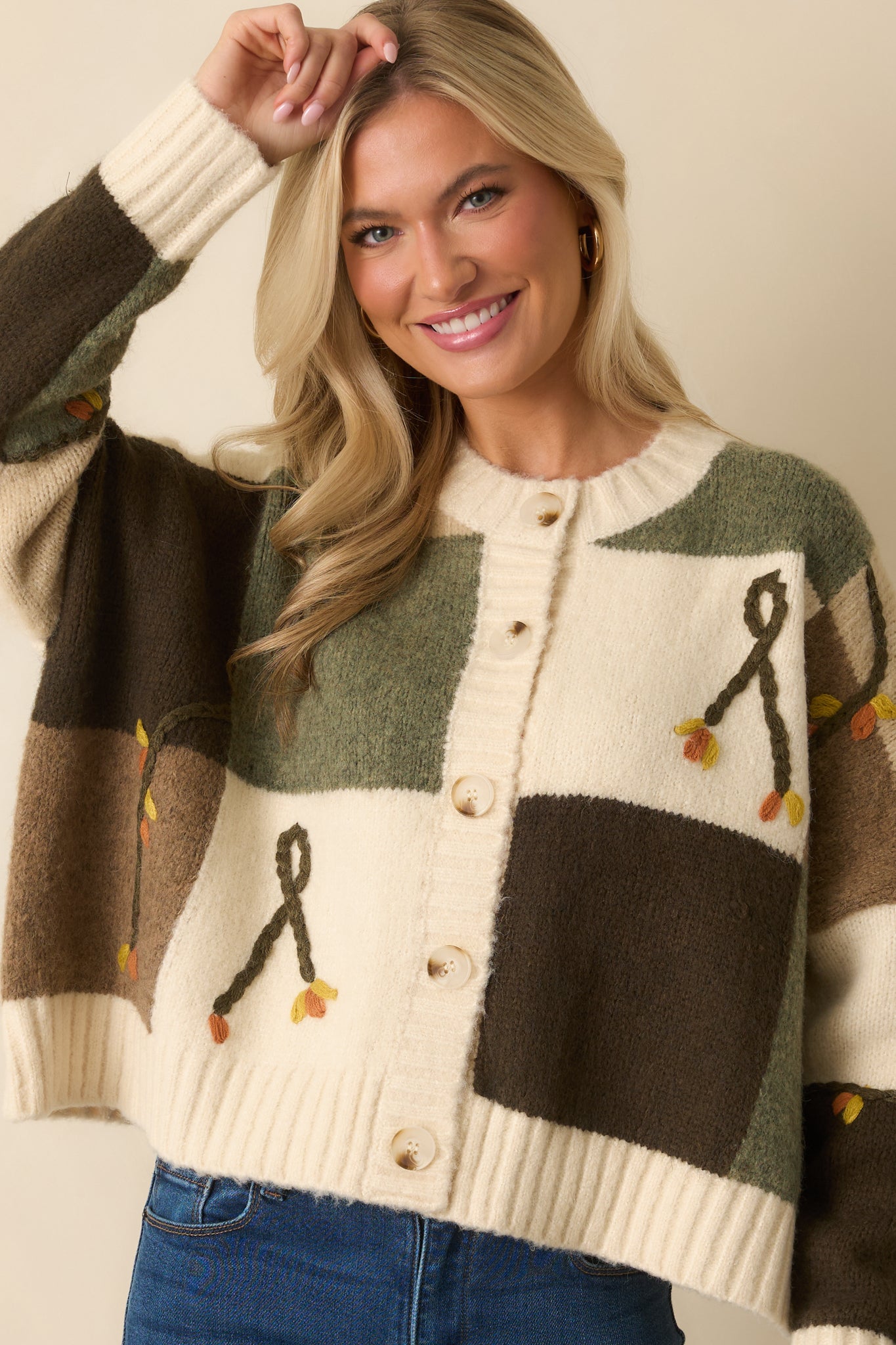 A cropped front view focusing on the colorblock knit pattern and ribbed hem of the ivory cardigan.