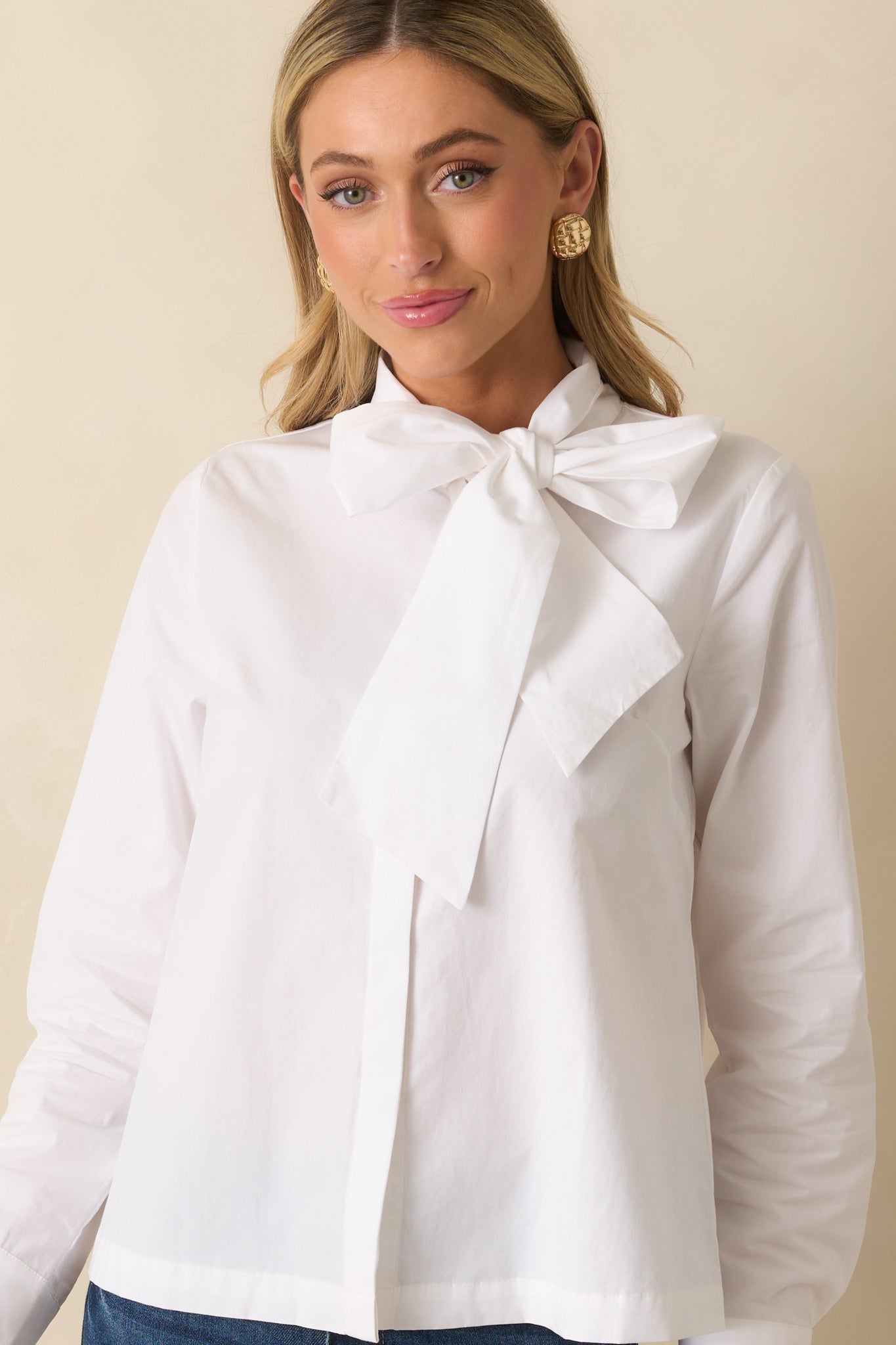 Cropped front view highlighting the self-tie bow neckline and functional button front of the white top.