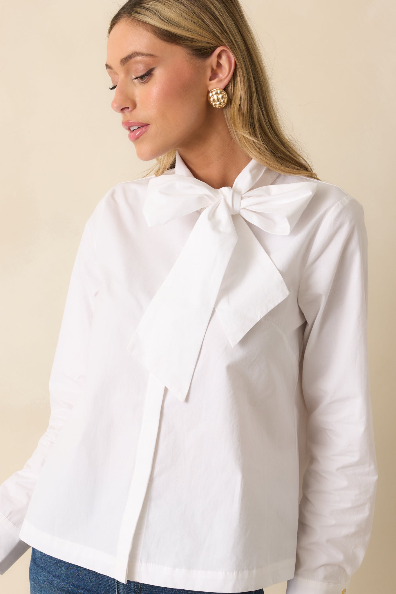 Cropped image focusing on the long sleeves and buttoned cuffs of the white relaxed-fit top.