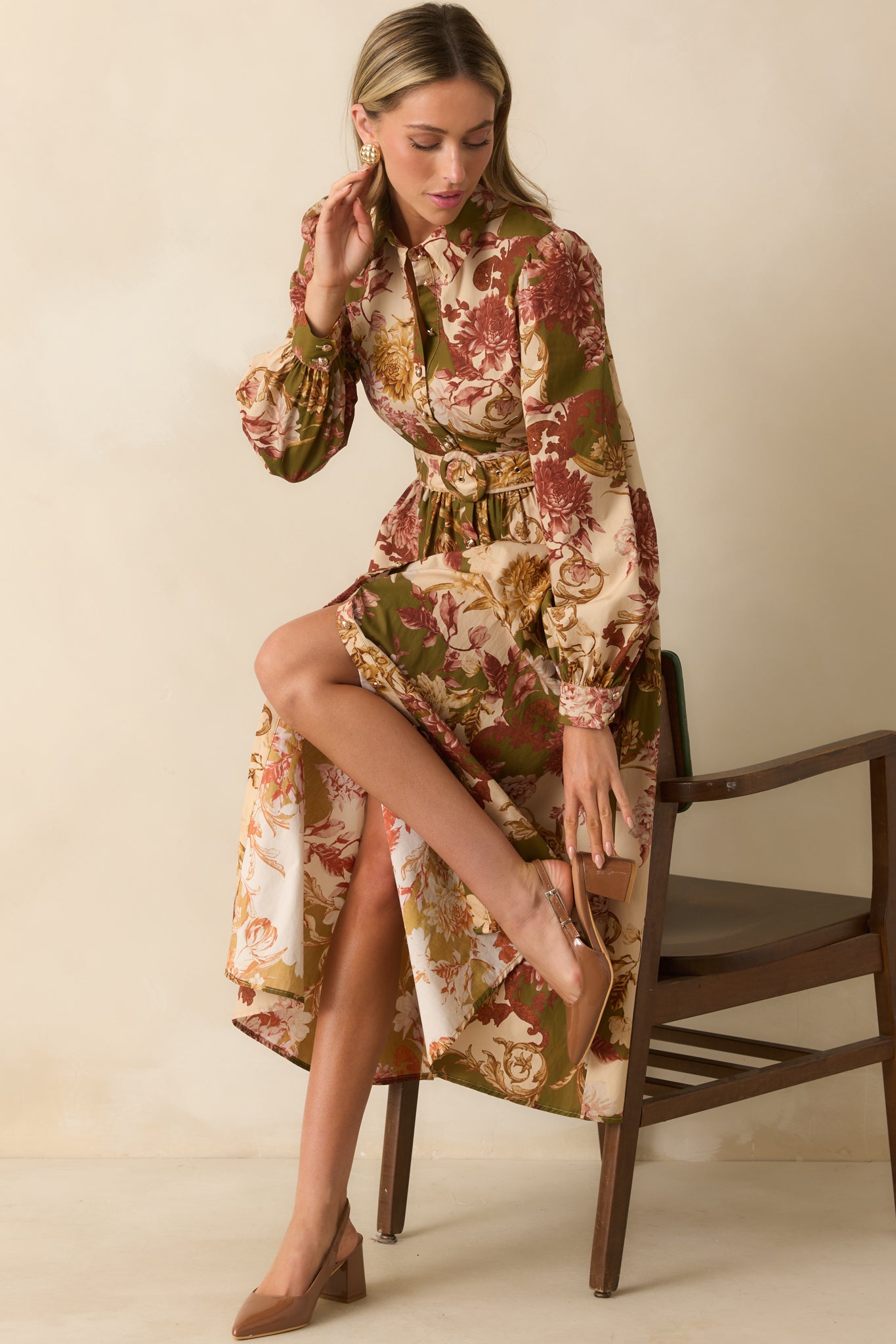 Olive green dress with multicolor floral print, collared neckline, long puff sleeves with button cuffs, and a functional button front, styled with optional waist belt.