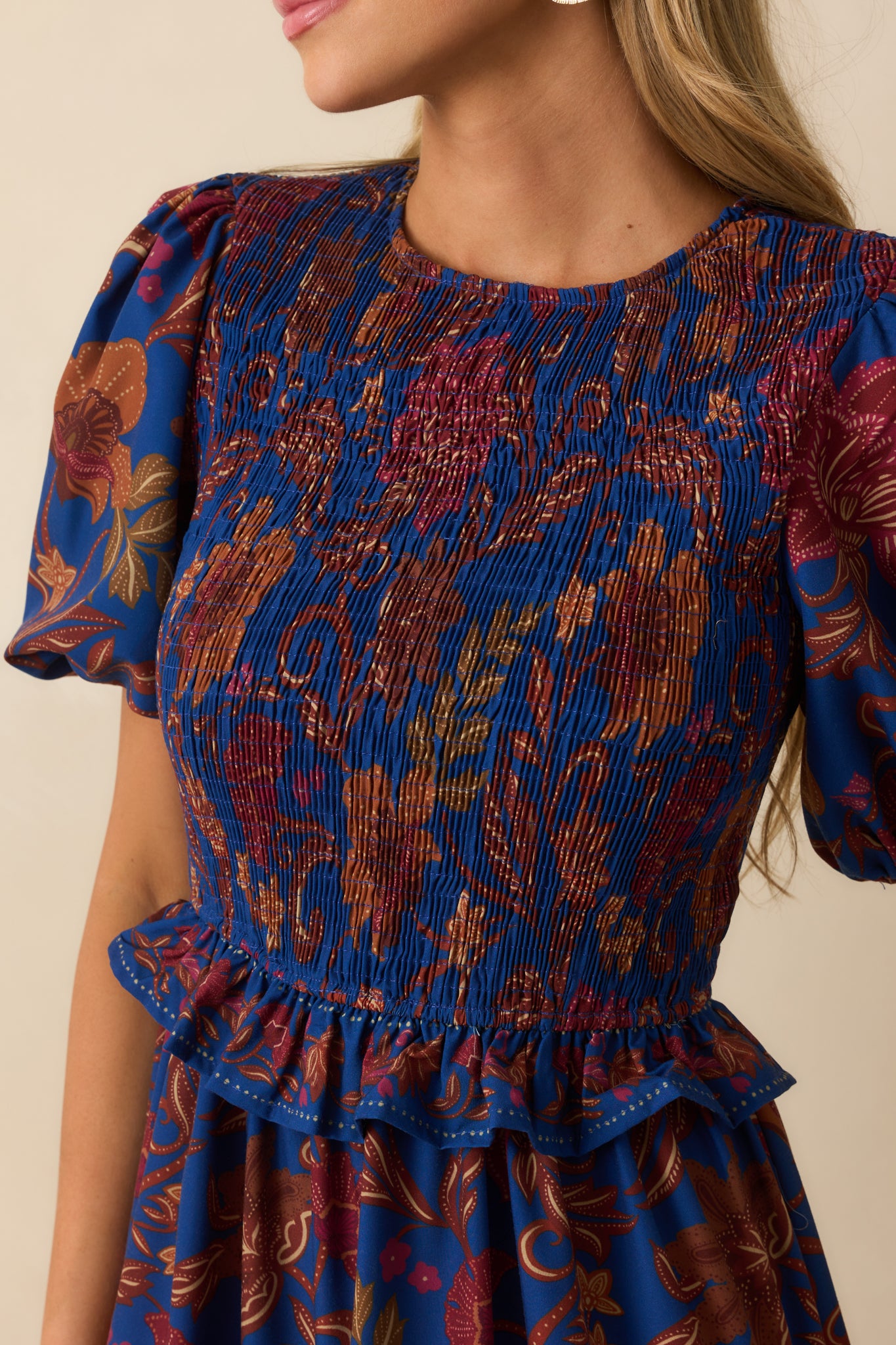 Detailed view of the smocked bodice, puff sleeve, and floral paisley print on the dress.