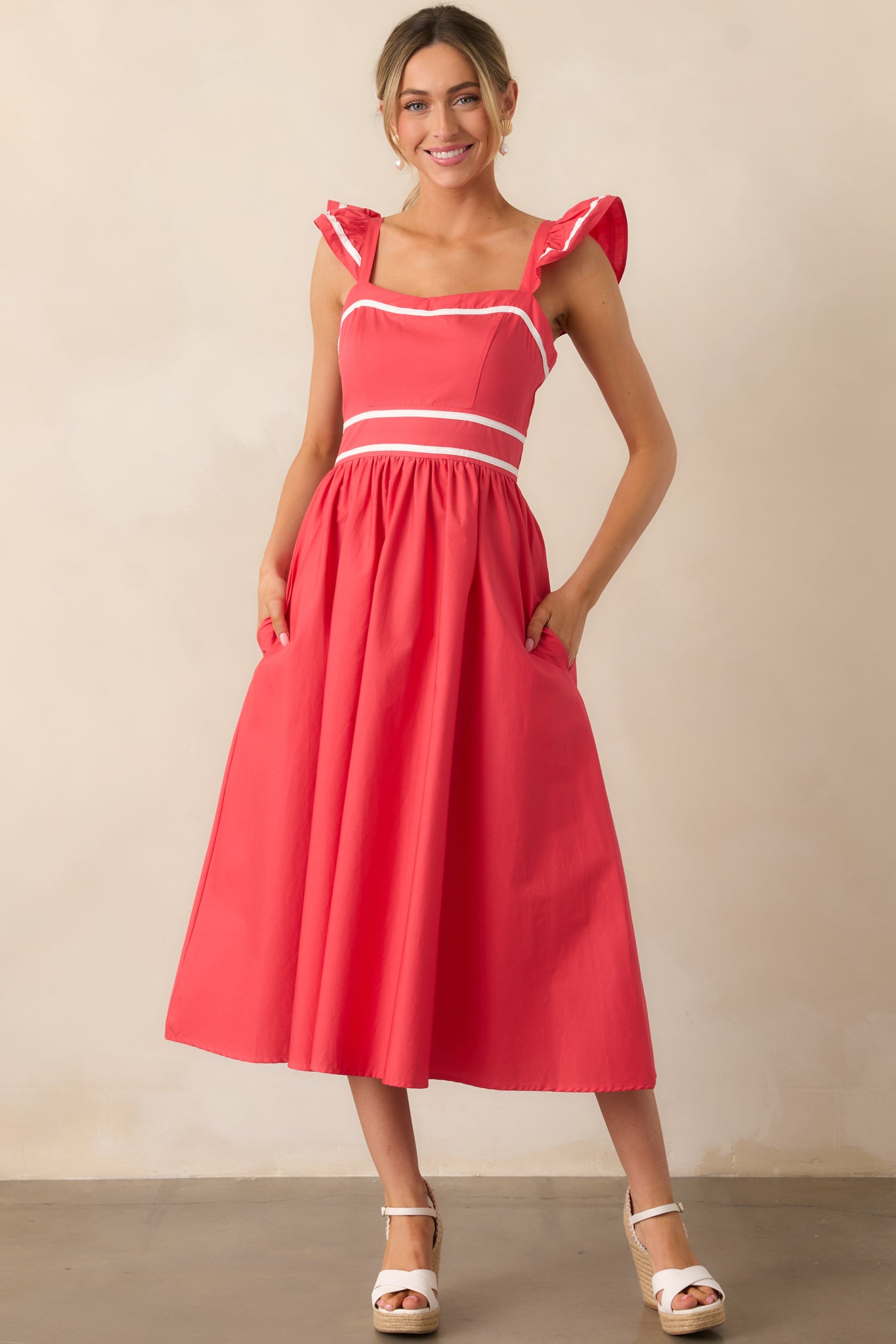 A tomato red dress featuring flutter sleeves, white hem detailing, and a flattering A-line silhouette.