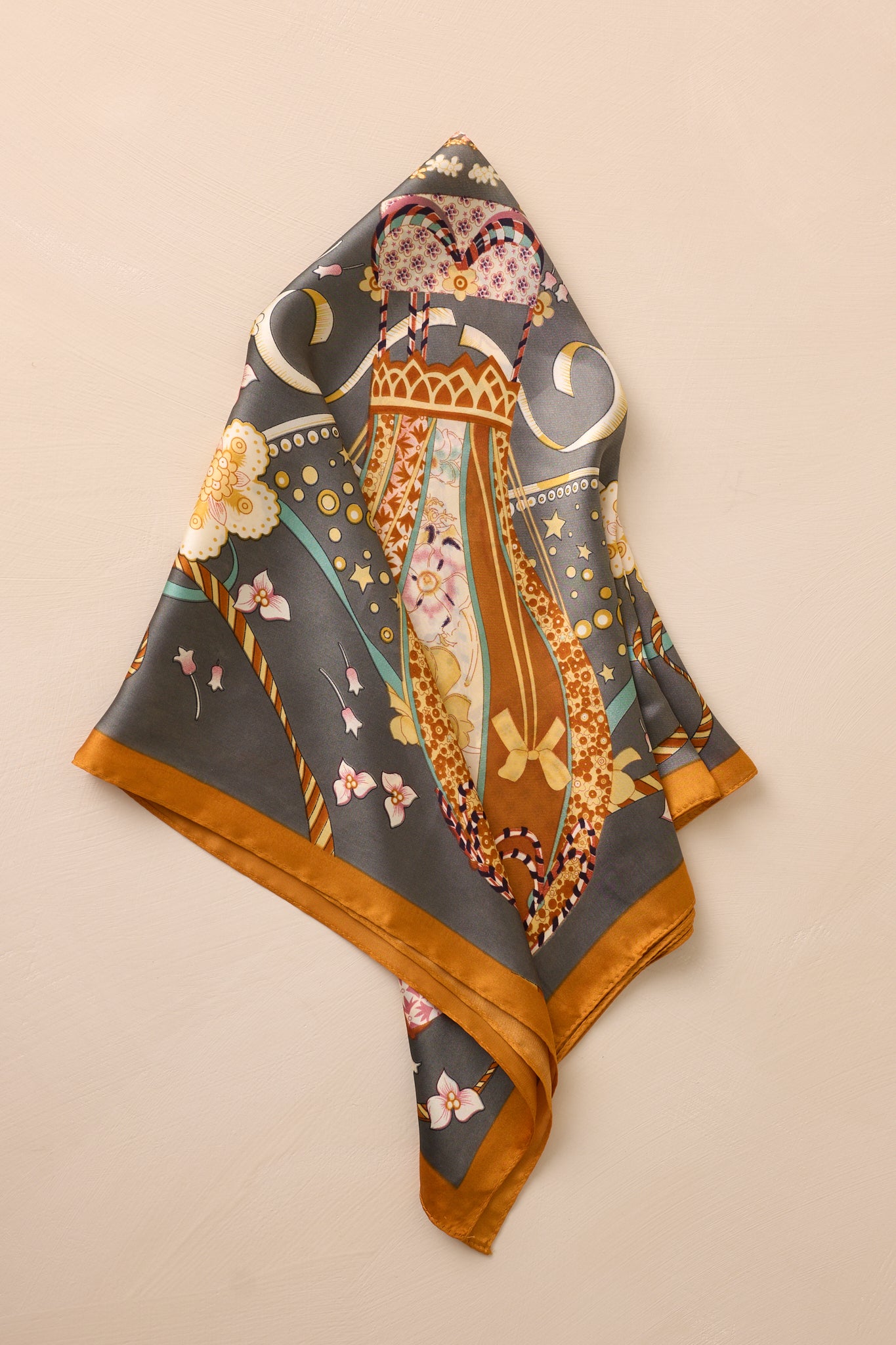 A shot of the slate gray satin scarf folded, featuring a glimpse of its colorful balloon pattern.