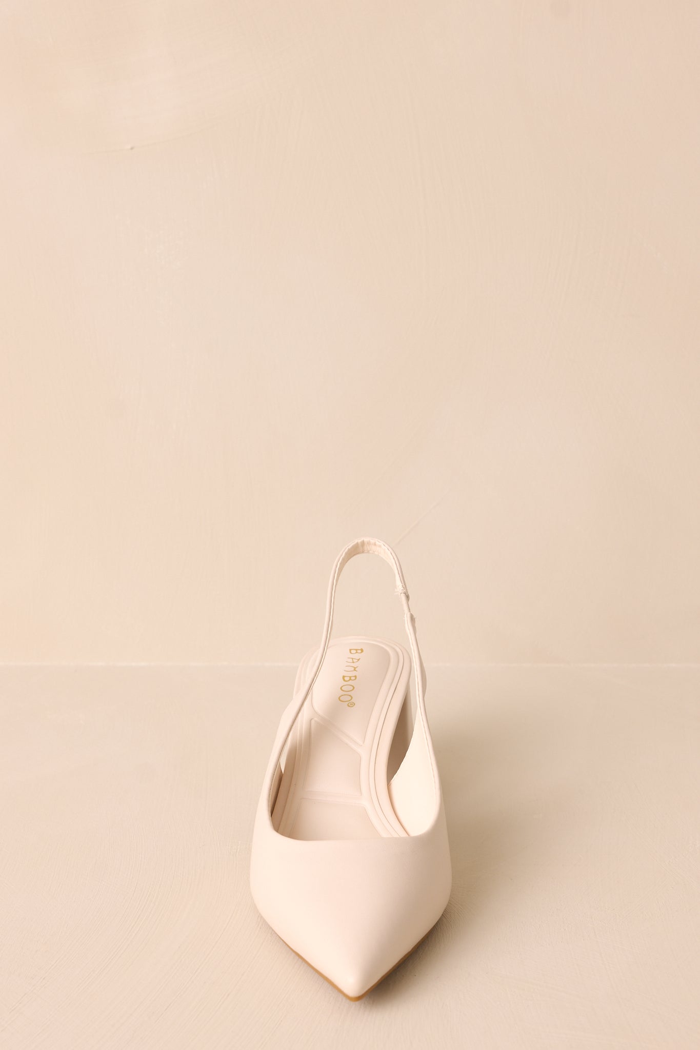 A close-up of the ivory heels' pointed toe and strap, focusing on the smooth faux leather material and the block heel that adds stability.