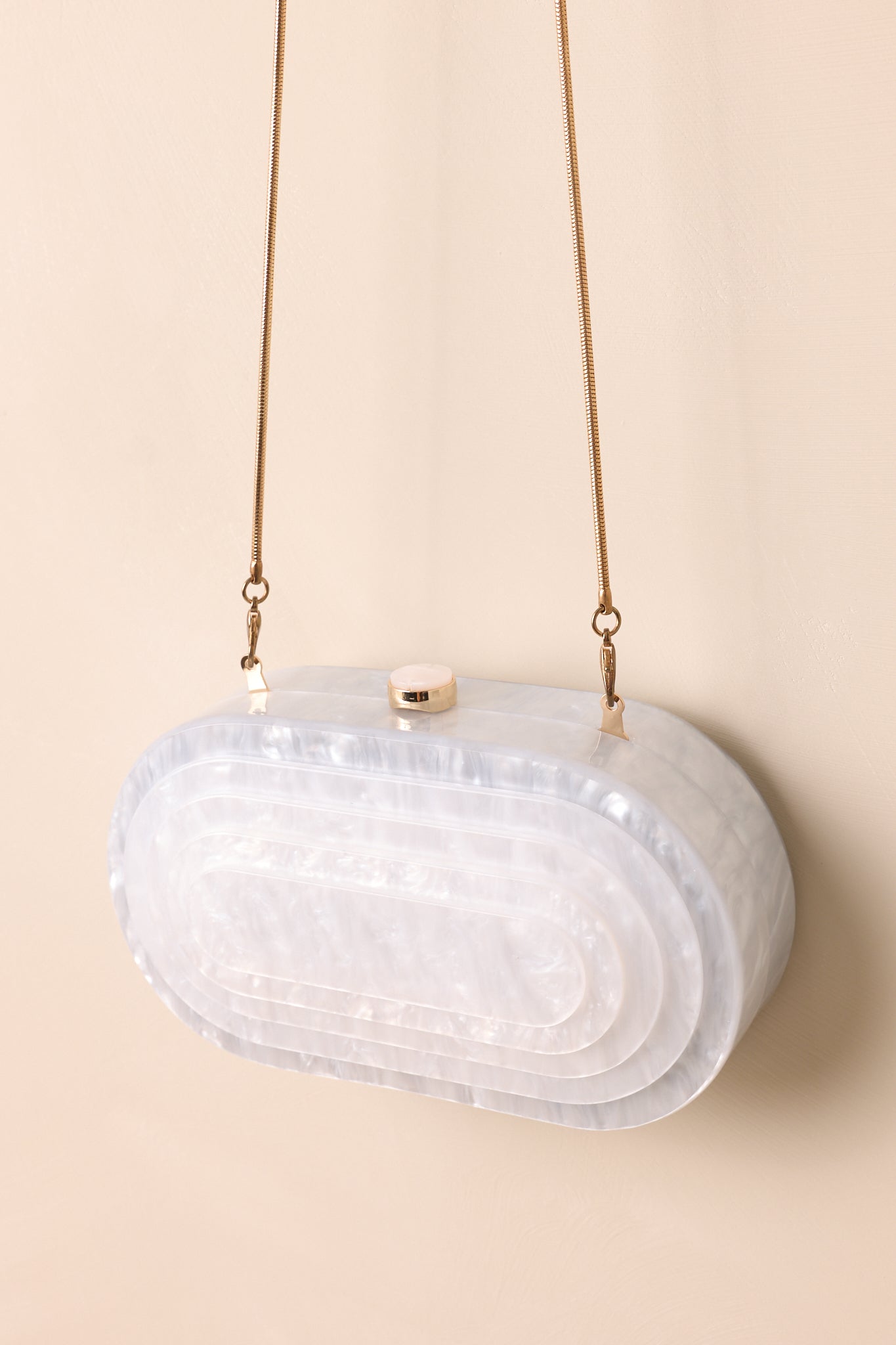 Close-up of the clutch showing the front layered design and gold crossbody chain attached.