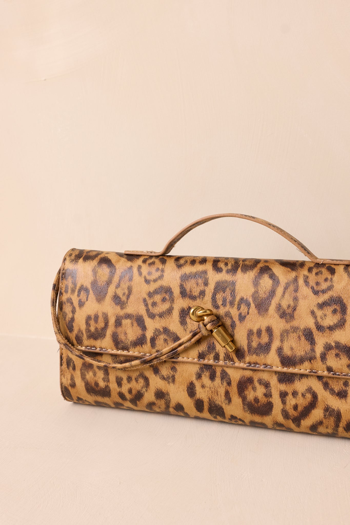 Close-up detail of the flap closure with gold hardware against the leopard print design.
