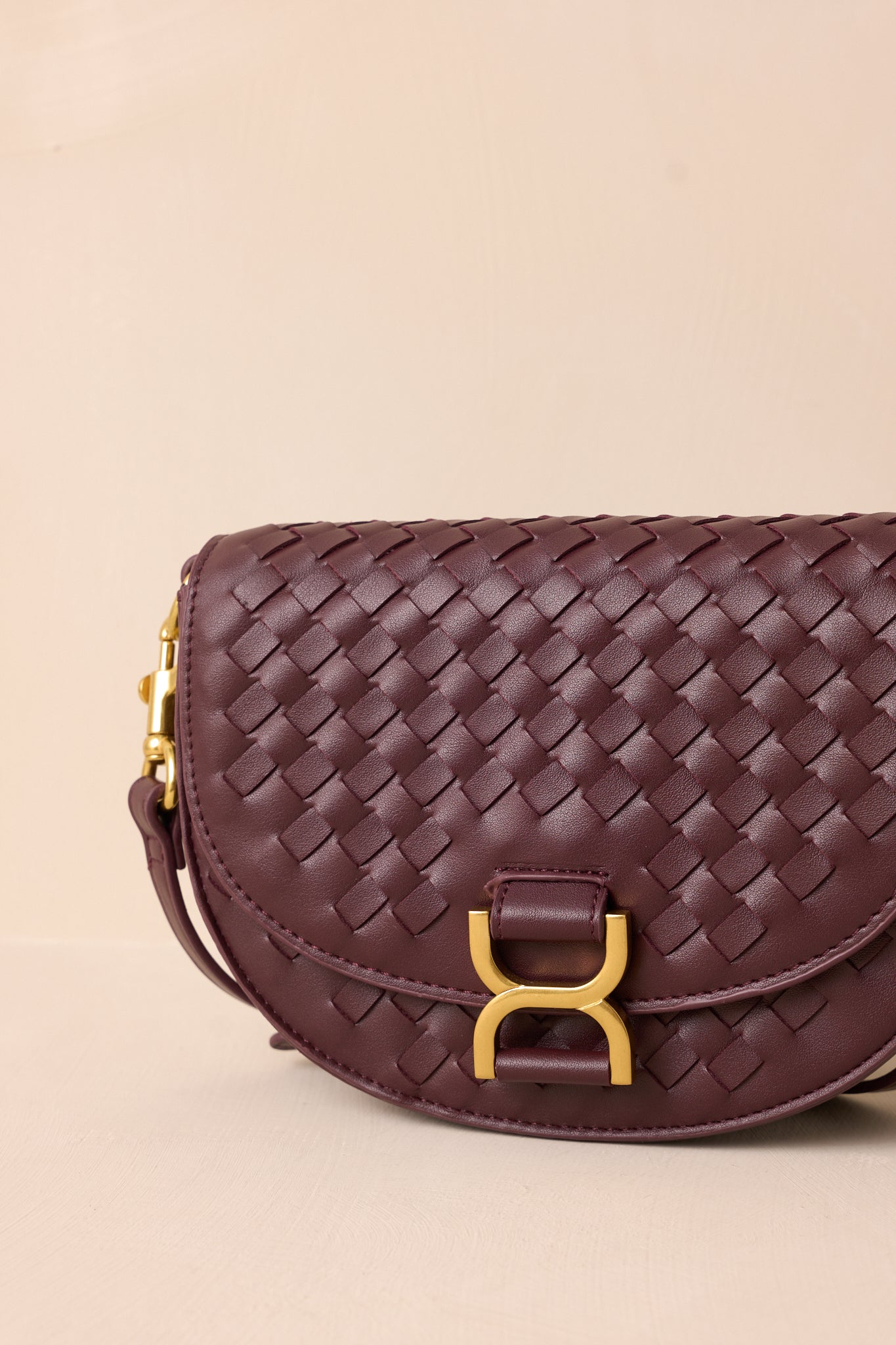 An extreme close-up of the handbag, showcasing the gold hardware, the woven faux leather texture, and the edge of the built-in inside pouch peeking out.