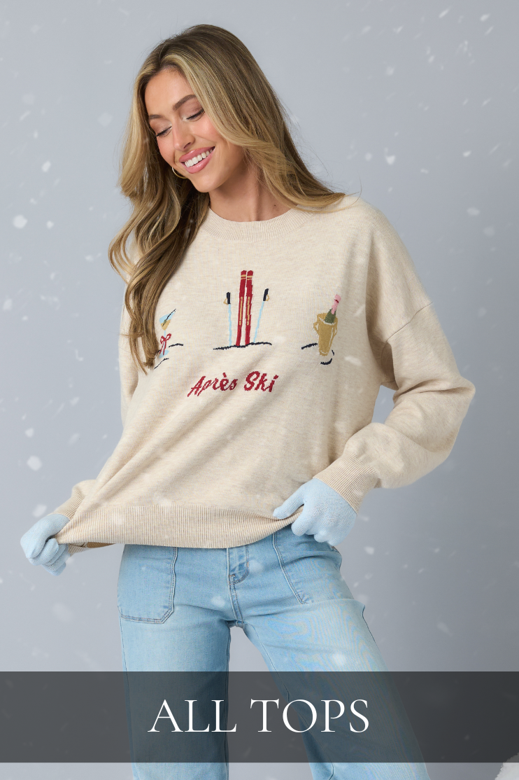 Women’s clothing tops including a cozy graphic Après Ski sweater styled with denim for a classic, casual look.