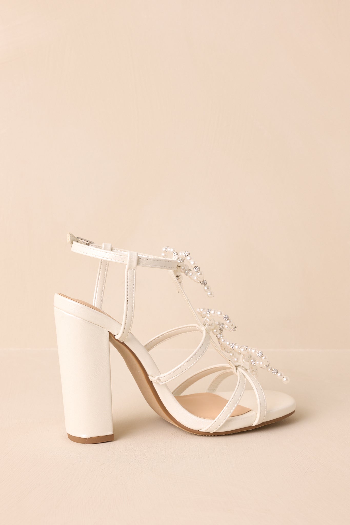An angled back view of the heels displaying the block heel shape, back of ankle straps, and subtle glitter finish.