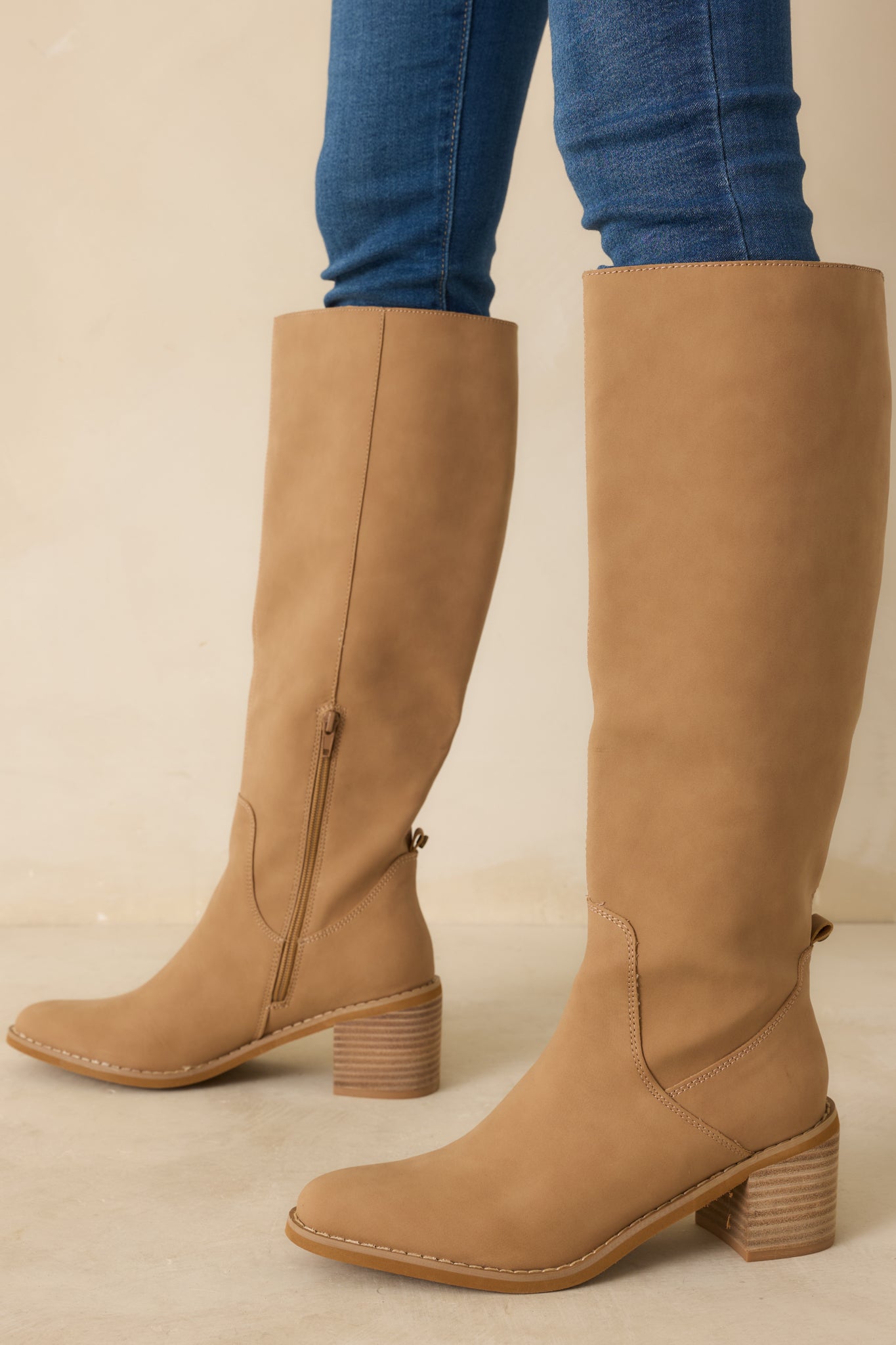 Angled cropped image highlighting the stacked block heel and sleek knee-high silhouette of the camel boots.