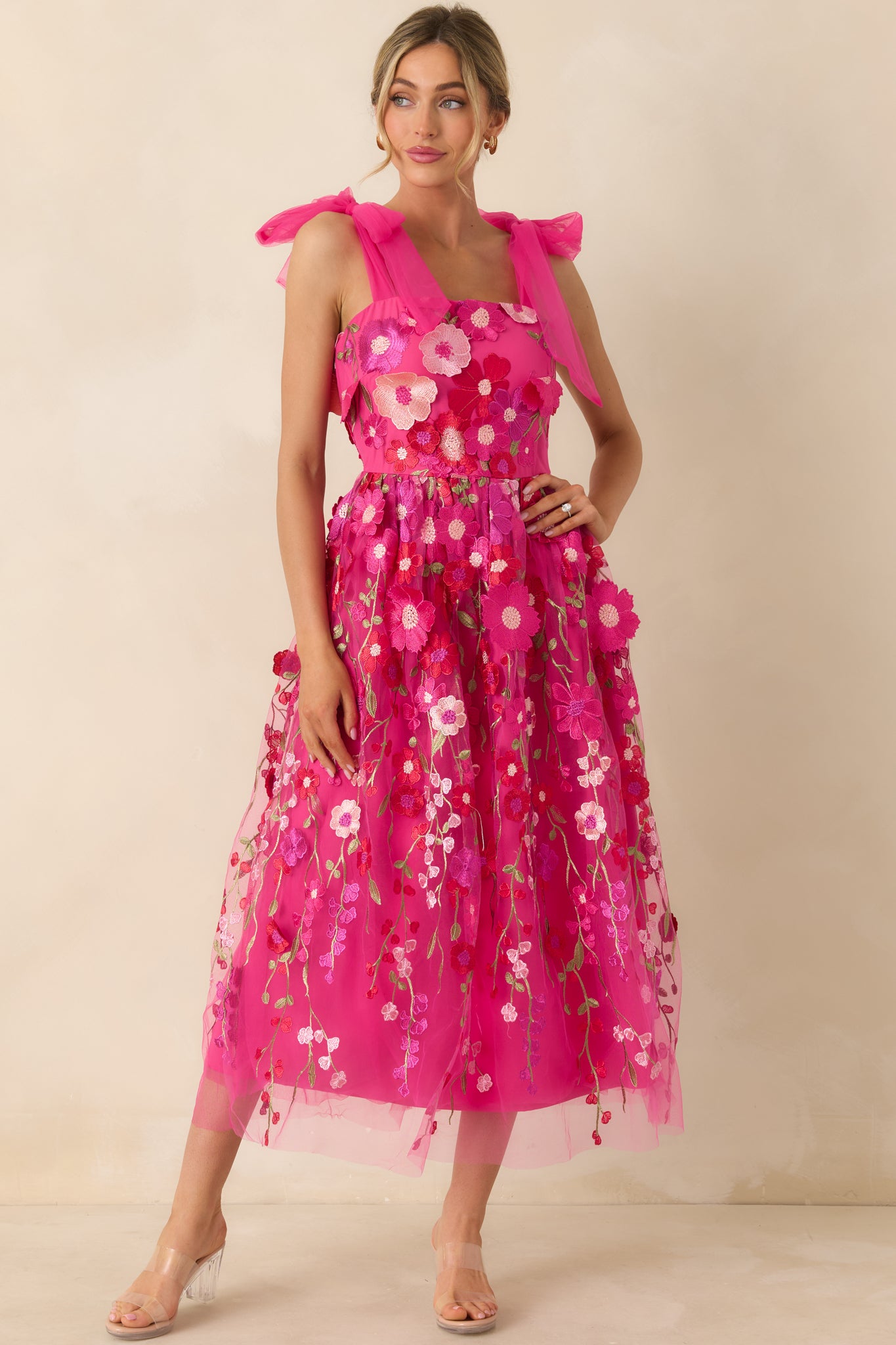 Angled front view highlighting the intricate floral appliqués and smooth, straight neckline of the fuchsia dress.